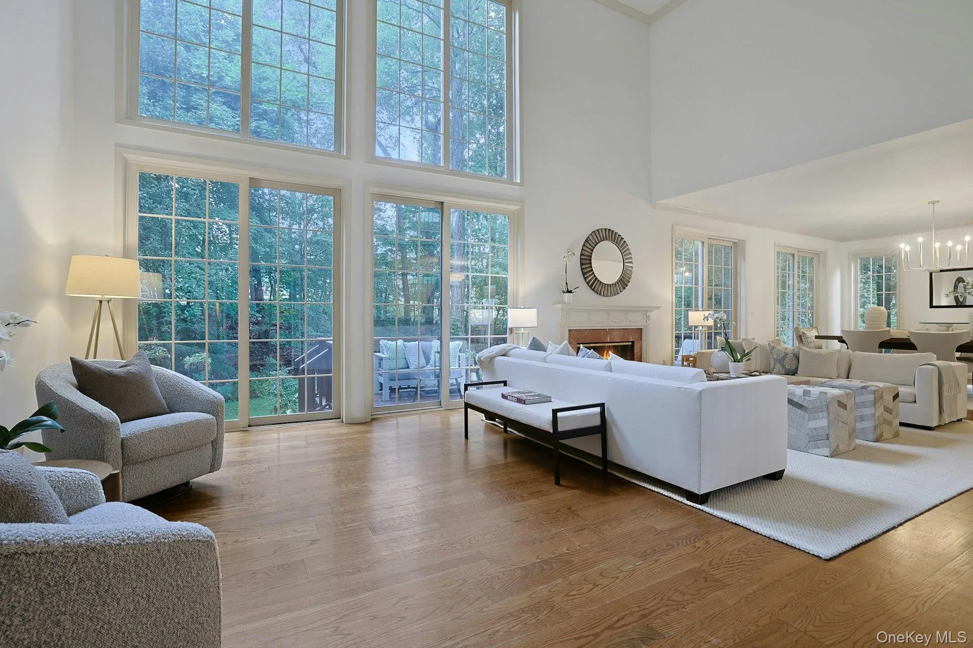 Soaring windows fill the living room with natural light and frame tranquil views of the mature trees surrounding the home. Soaring windows fill the living room with natural light and frame tranquil views of the mature trees surrounding the home.