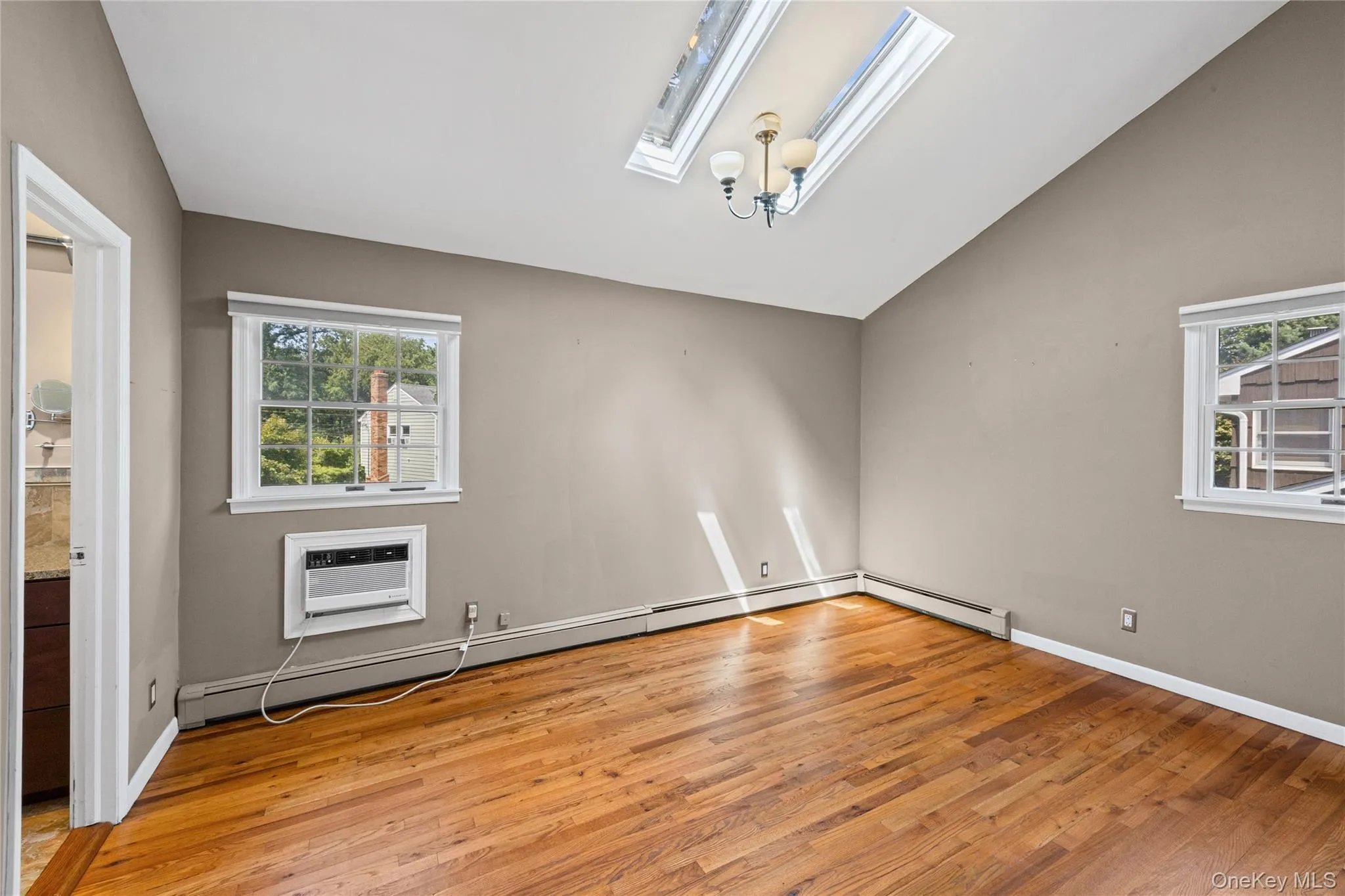 Light and bright primary bedroom with vaulted ceiling, skylights, walk in closet and access to full bath Light and bright primary bedroom with vaulted ceiling, skylights, walk in closet and access to full bath