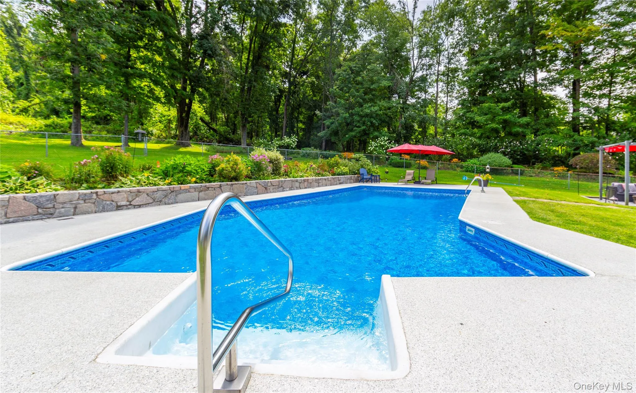 Surrounded by lush landscaping, vibrant perennial gardens framed by a stone wall. Surrounded by lush landscaping, vibrant perennial gardens framed by a stone wall.