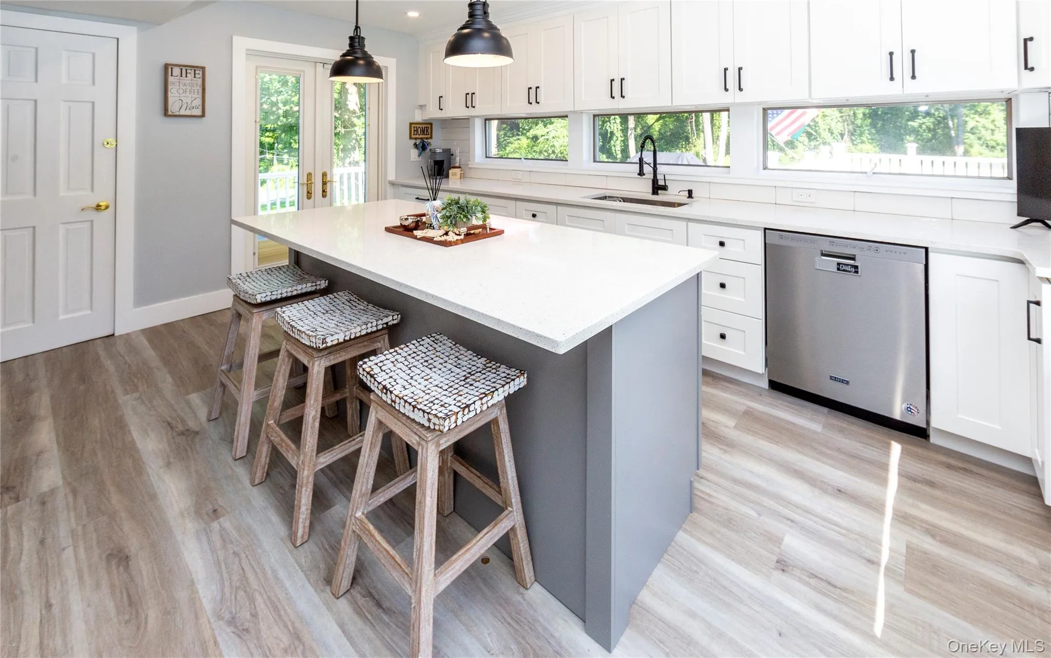 Light-filled culinary space surrounded by windows and French doors on three sides offering peaceful outdoor views. Light-filled culinary space surrounded by windows and French doors on three sides offering peaceful outdoor views.