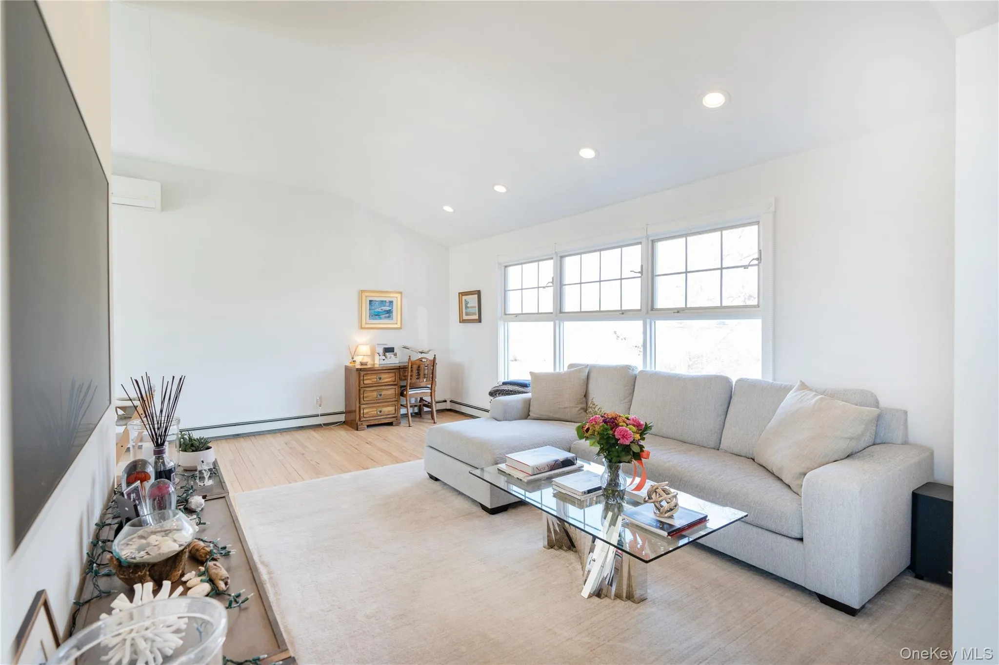 Living room with lofted ceiling, light wood-style floors, a baseboard heating unit, and recessed lighting Living room with lofted ceiling, light wood-style floors, a baseboard heating unit, and recessed lighting