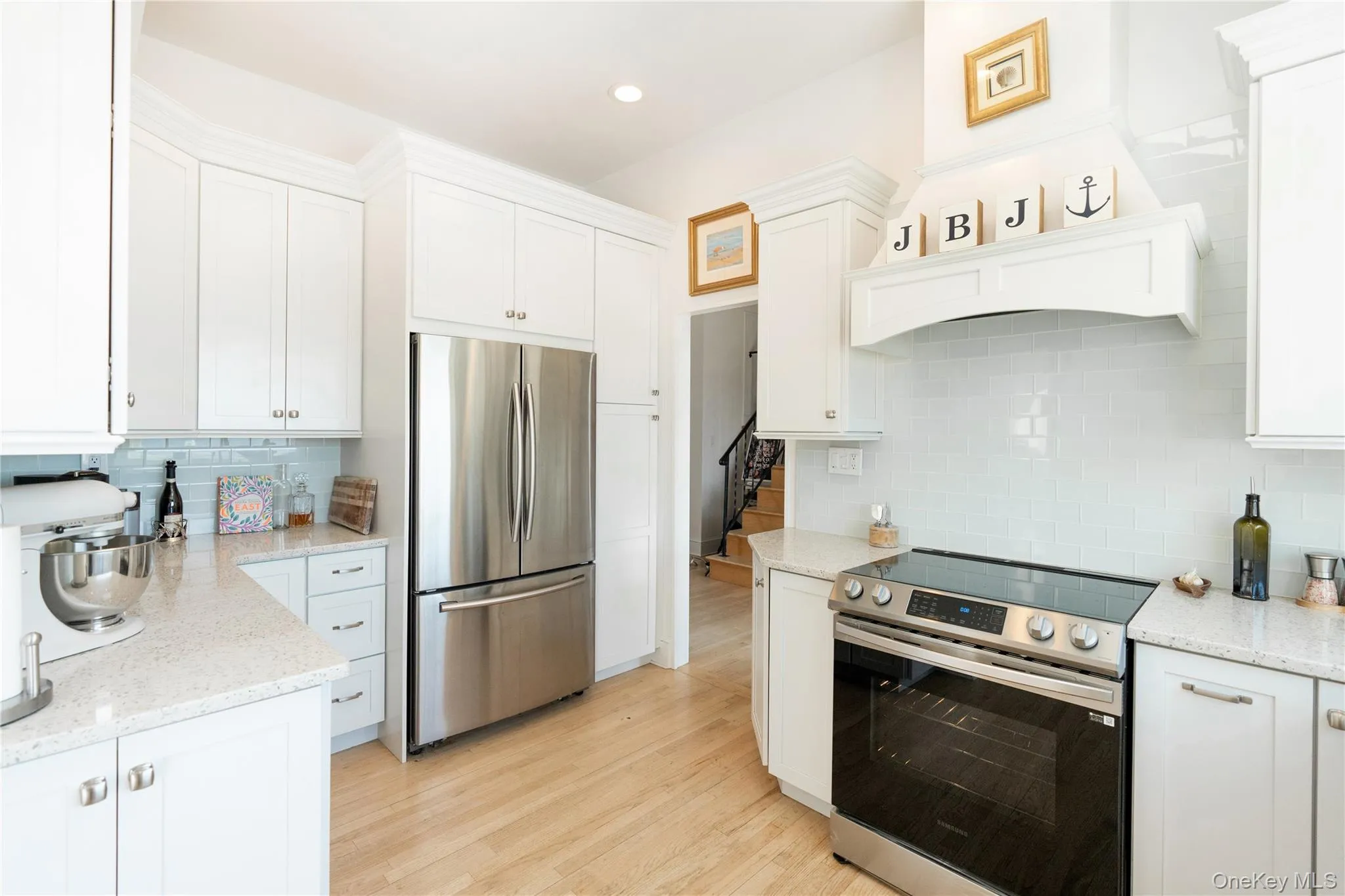 Kitchen with white cabinetry, decorative backsplash, stainless steel appliances, and light wood-type flooring Kitchen with white cabinetry, decorative backsplash, stainless steel appliances, and light wood-type flooring