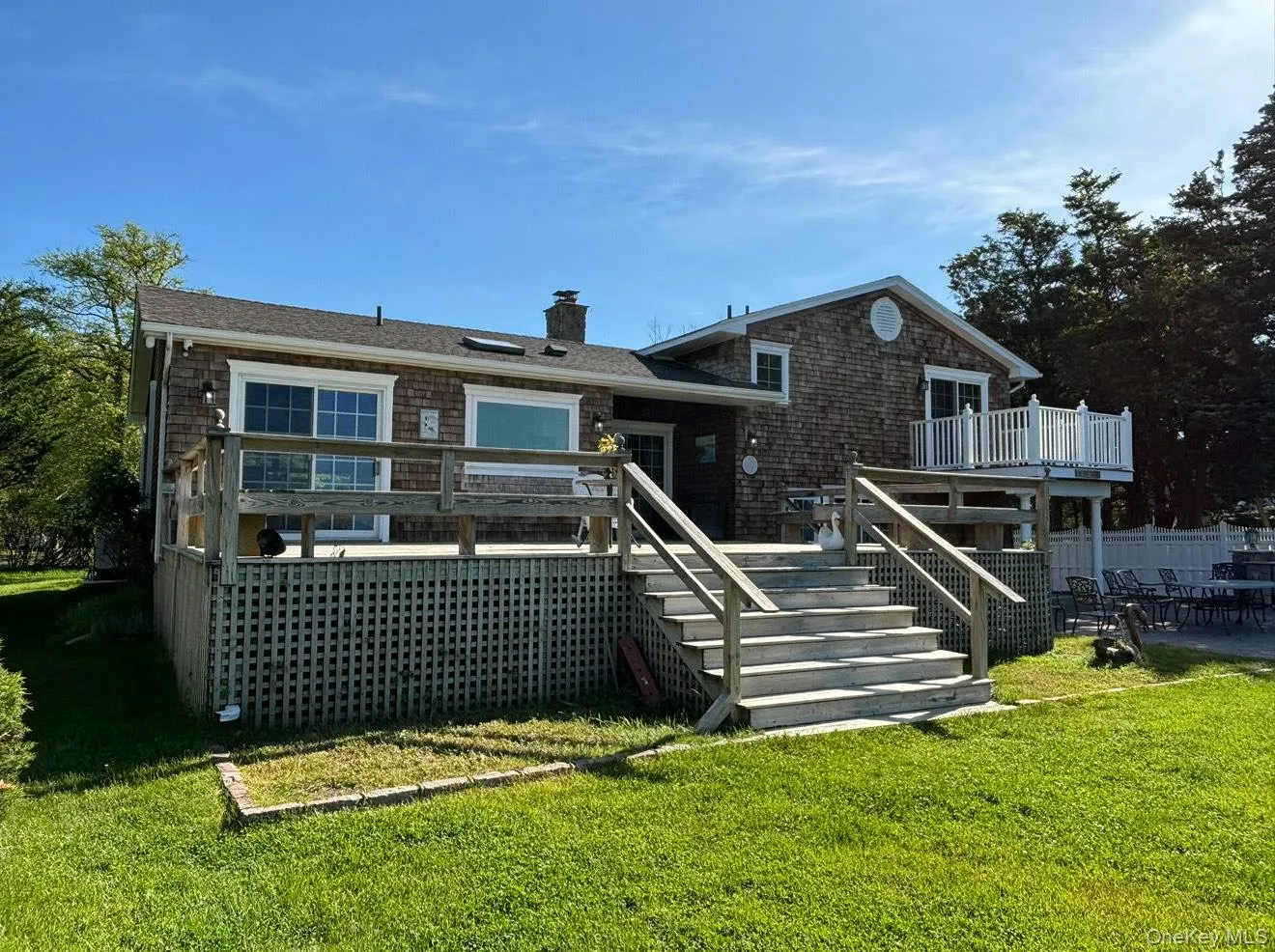 Back of property featuring a chimney, a wooden deck, stairs, and a lawn Back of property featuring a chimney, a wooden deck, stairs, and a lawn