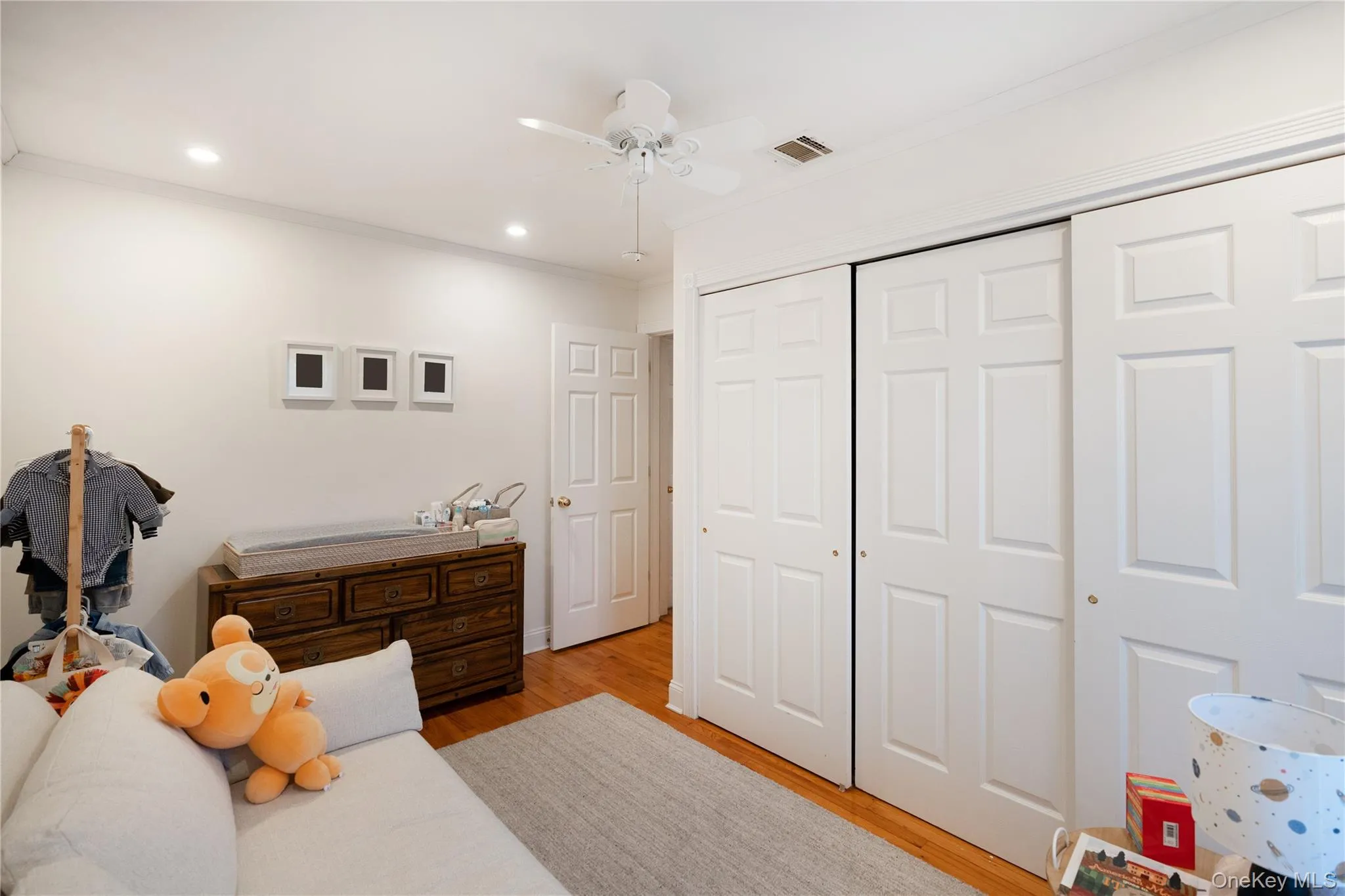 Bedroom featuring a closet, light wood-style flooring, visible vents, and crown molding Bedroom featuring a closet, light wood-style flooring, visible vents, and crown molding