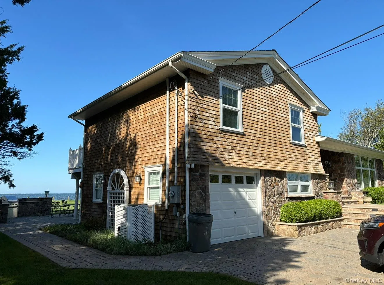 View of property exterior featuring decorative driveway, stone siding, and a garage View of property exterior featuring decorative driveway, stone siding, and a garage
