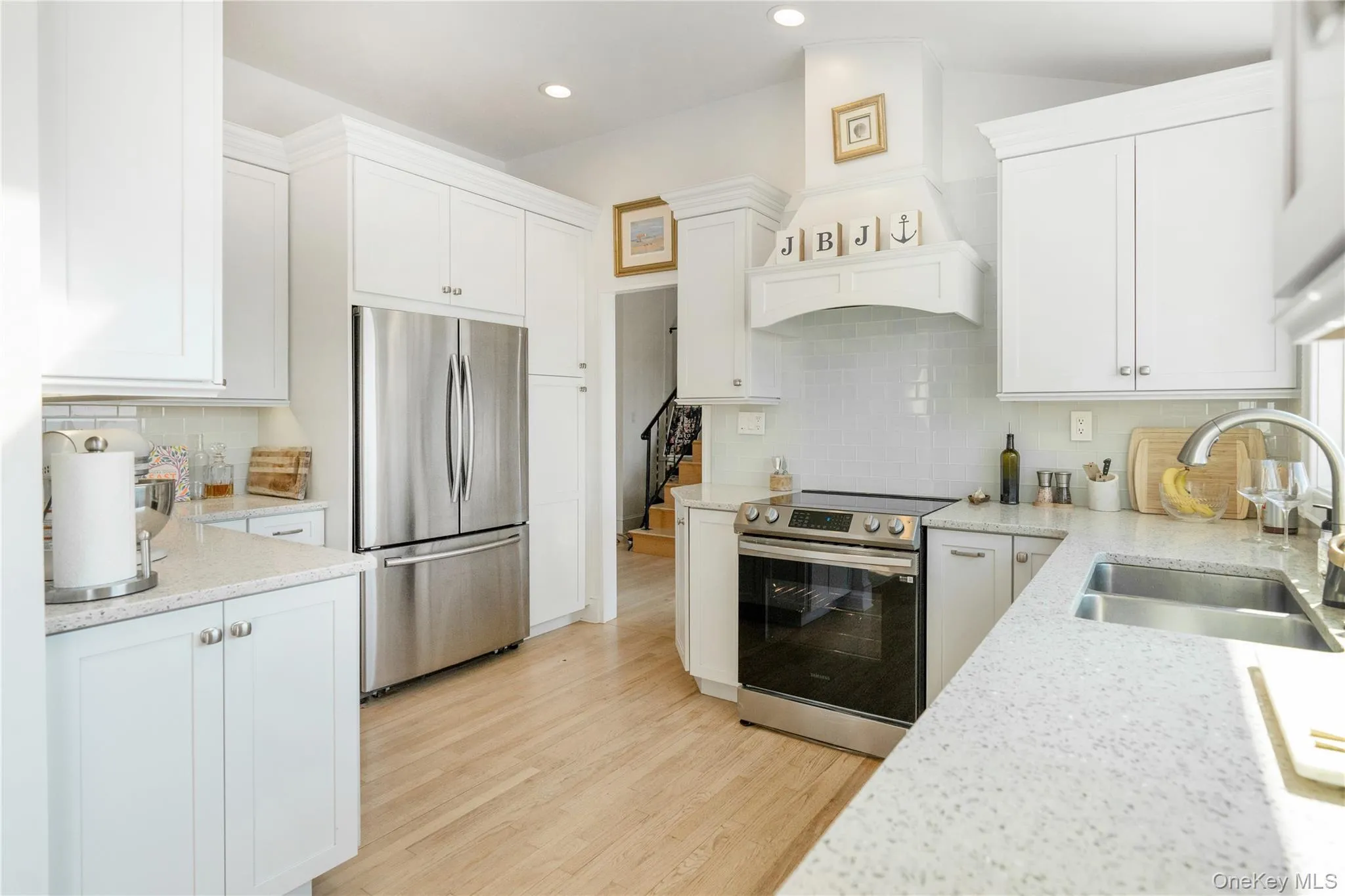 Kitchen featuring white cabinets, light wood-style flooring, a sink, and stainless steel appliances Kitchen featuring white cabinets, light wood-style flooring, a sink, and stainless steel appliances