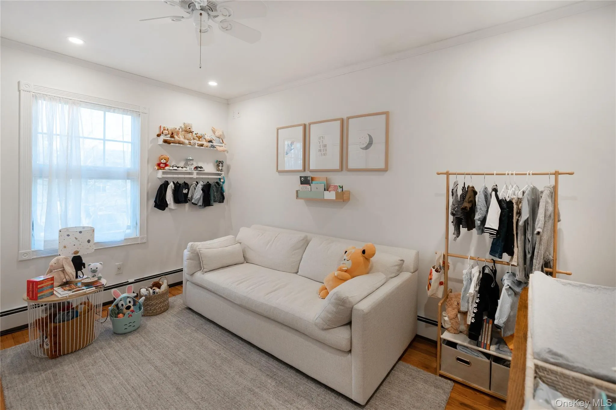 Living room featuring baseboard heating, wood finished floors, ornamental molding, and a ceiling fan Living room featuring baseboard heating, wood finished floors, ornamental molding, and a ceiling fan
