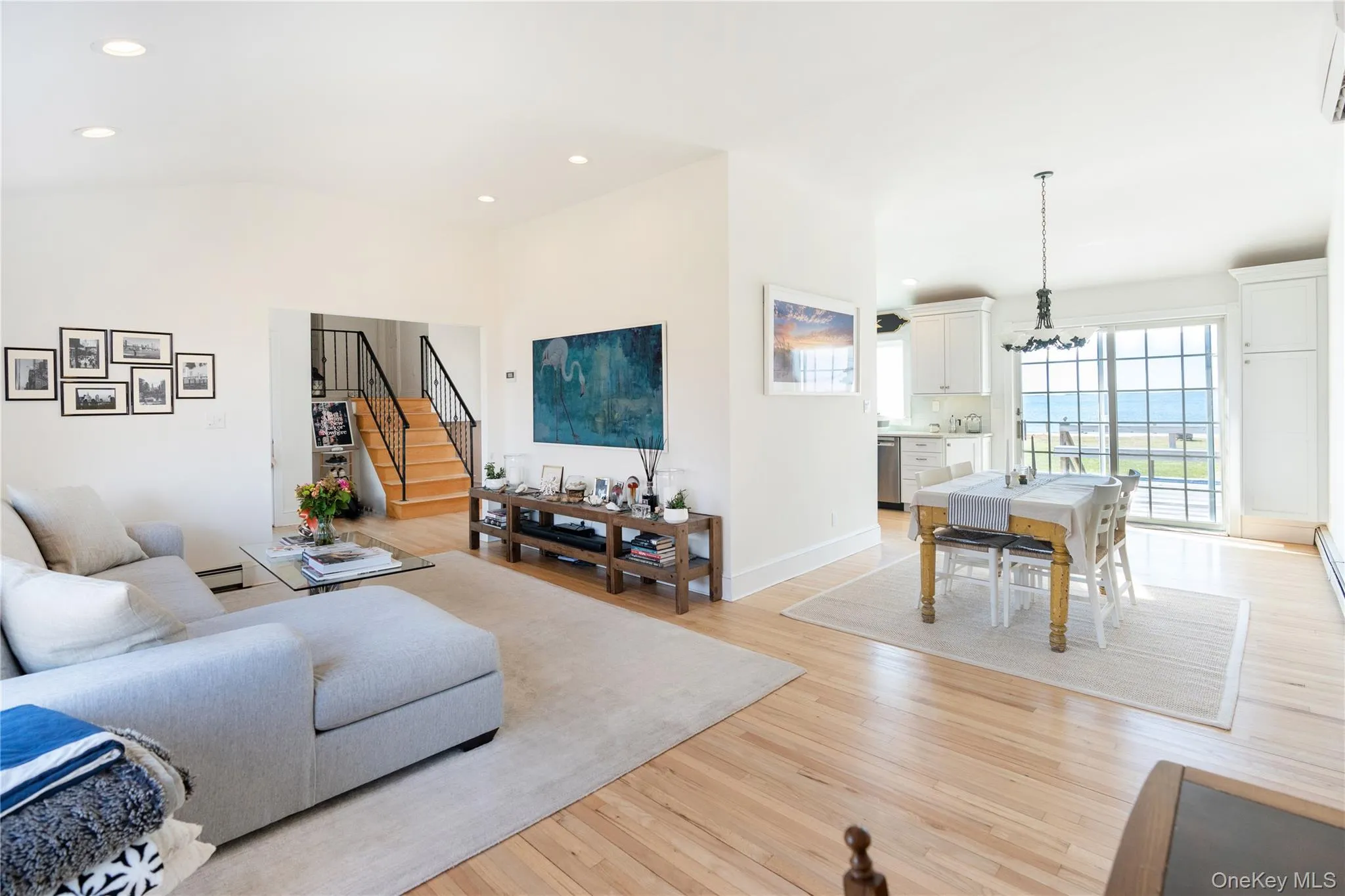 Living area featuring stairway, recessed lighting, a baseboard radiator, light wood-style flooring, and a notable chandelier Living area featuring stairway, recessed lighting, a baseboard radiator, light wood-style flooring, and a notable chandelier
