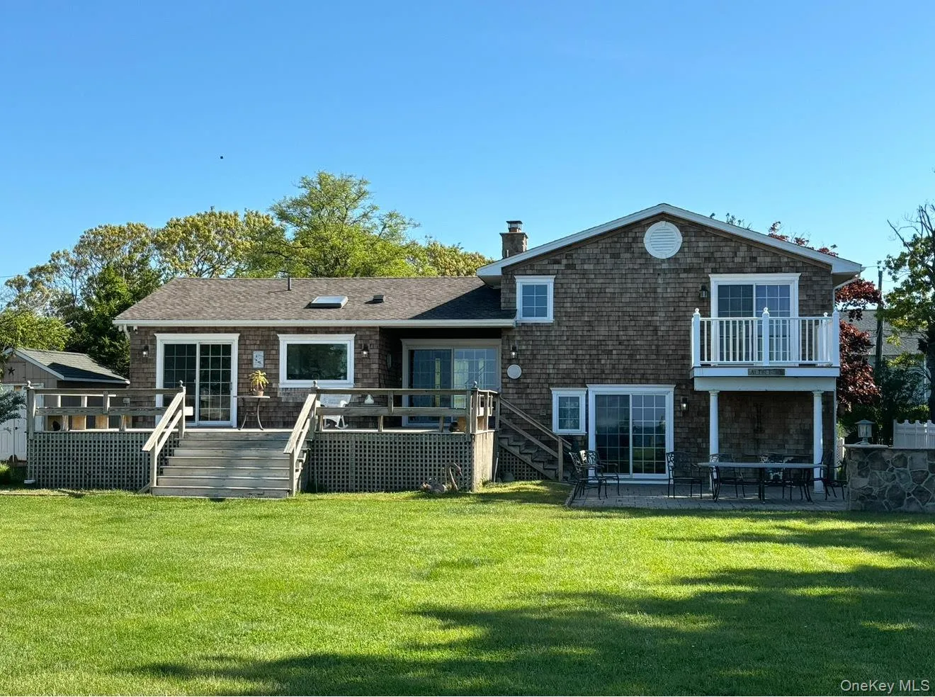 Rear view of property featuring a chimney, a lawn, stairs, a deck, and a shingled roof Rear view of property featuring a chimney, a lawn, stairs, a deck, and a shingled roof