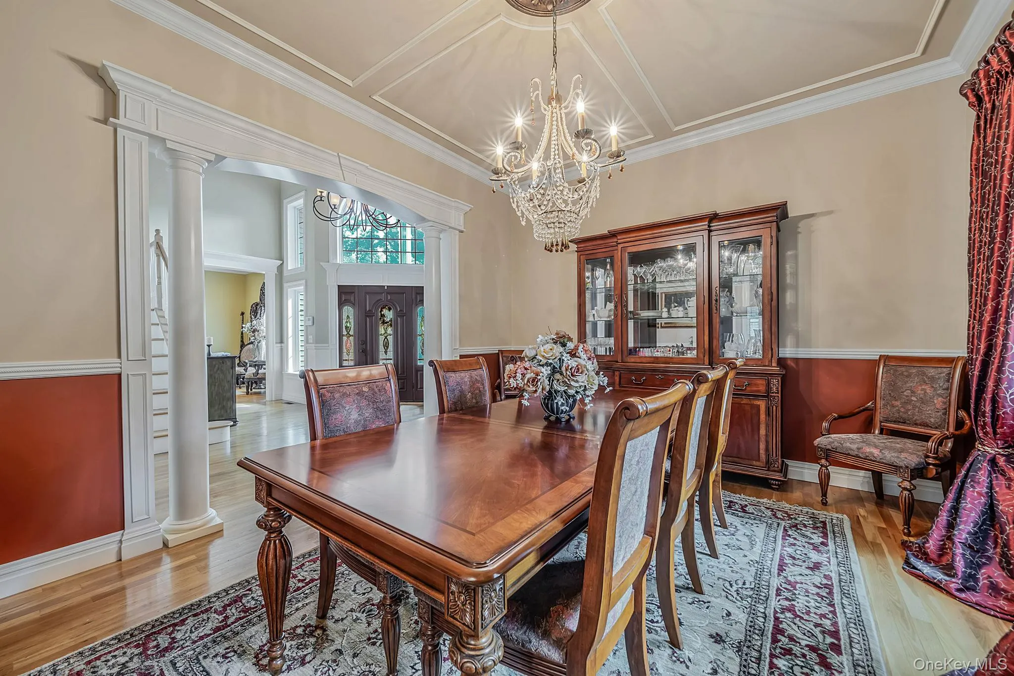 Hardwood flooring, decorative wall molding, tray ceiling, crystal chandelier, and arched entryway with columns Hardwood flooring, decorative wall molding, tray ceiling, crystal chandelier, and arched entryway with columns