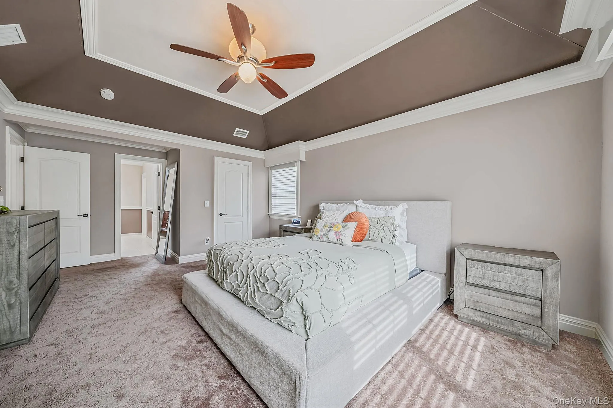 Tray ceiling with crown molding, ceiling fan, and carpeted flooring Tray ceiling with crown molding, ceiling fan, and carpeted flooring