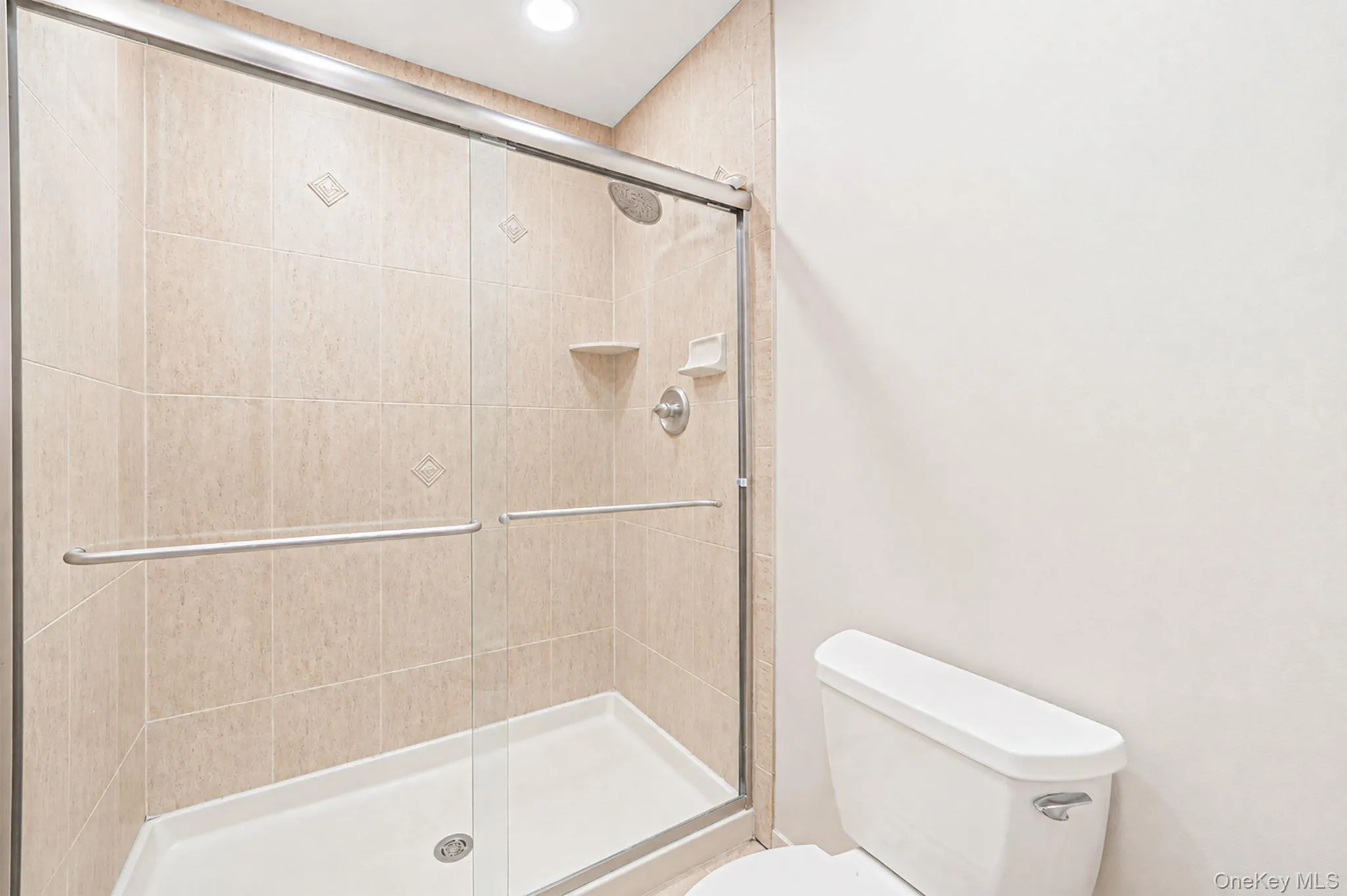 Glass-enclosed shower with tile surround and overhead recessed lighting Glass-enclosed shower with tile surround and overhead recessed lighting
