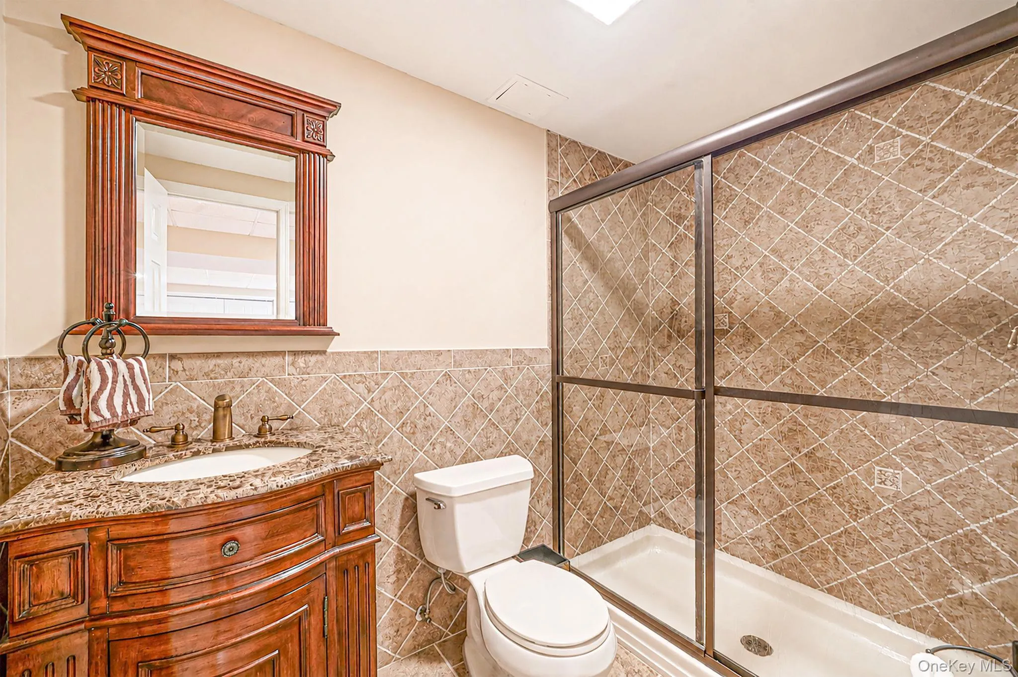 Vanity with a granite countertop, decorative wood-framed mirror, and a walk-in shower with sliding glass doors Vanity with a granite countertop, decorative wood-framed mirror, and a walk-in shower with sliding glass doors