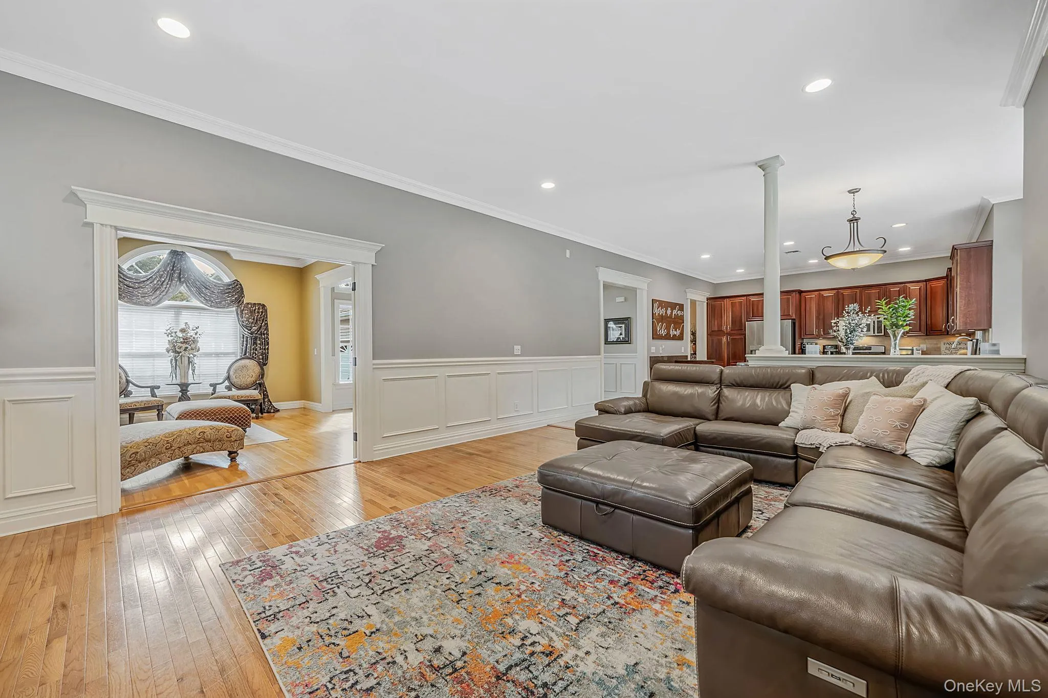 Hardwood flooring extending through the living area, wainscoting, decorative crown molding, recessed lighting, and a column accent Hardwood flooring extending through the living area, wainscoting, decorative crown molding, recessed lighting, and a column accent