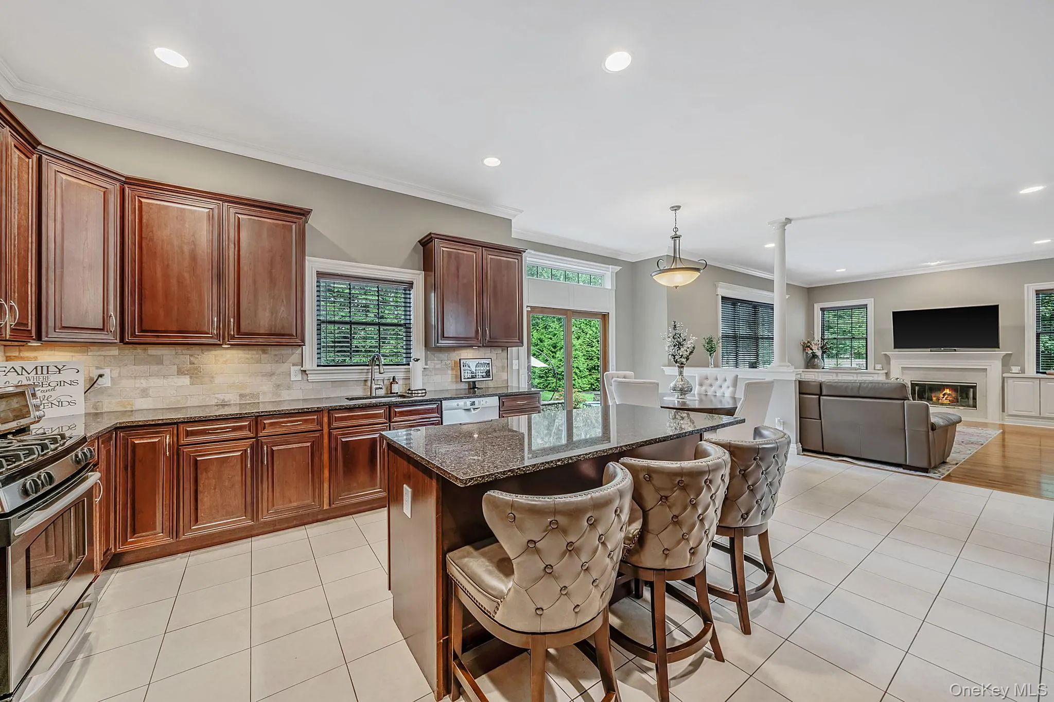 Kitchen featuring extensive wood cabinetry, stainless steel appliances, a large center island with a granite countertop, and tile flooring Kitchen featuring extensive wood cabinetry, stainless steel appliances, a large center island with a granite countertop, and tile flooring