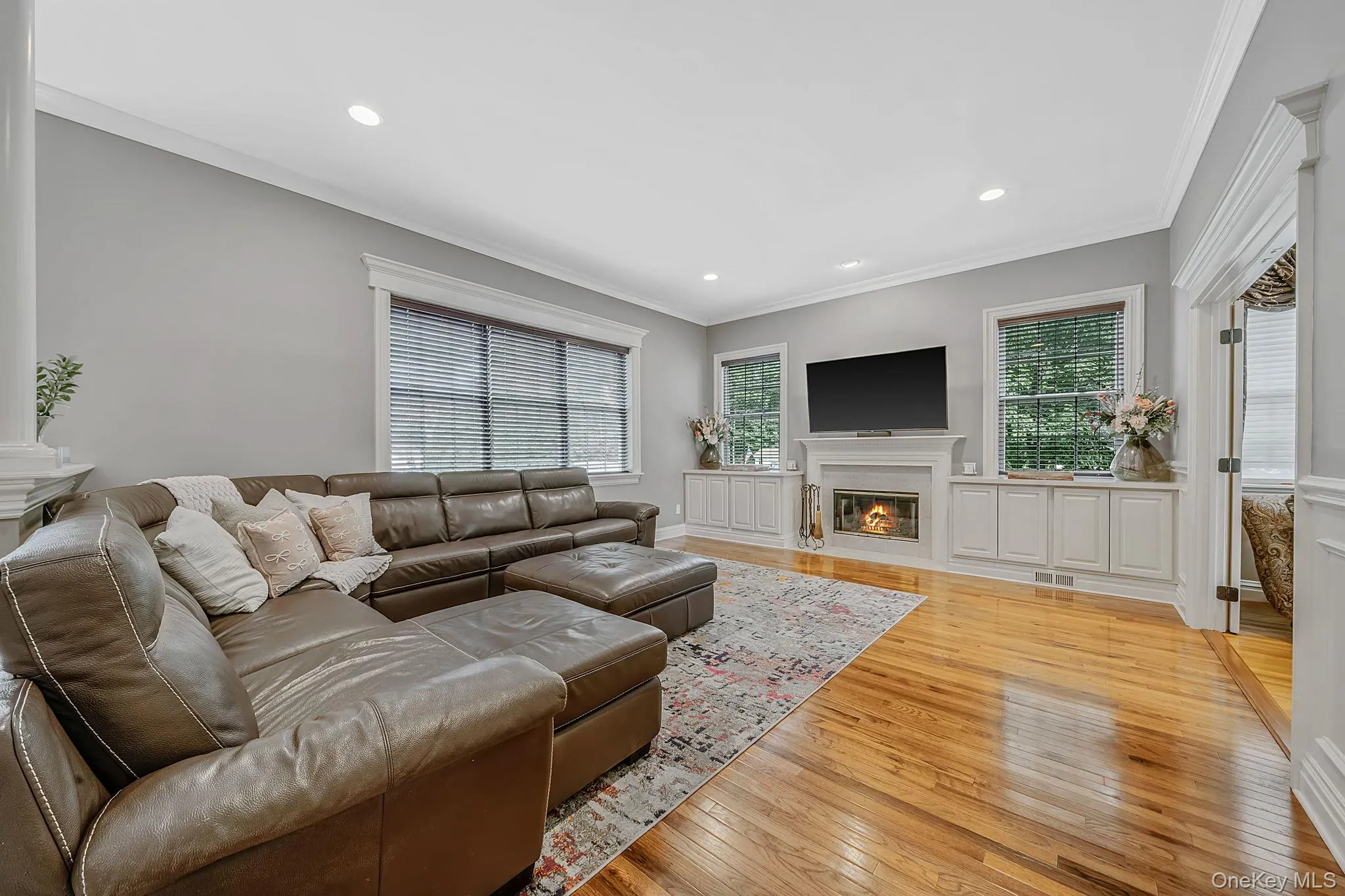 Hardwood flooring, recessed lighting, crown molding, built-in cabinetry, and a wood burning fireplace with a mantel Hardwood flooring, recessed lighting, crown molding, built-in cabinetry, and a wood burning fireplace with a mantel