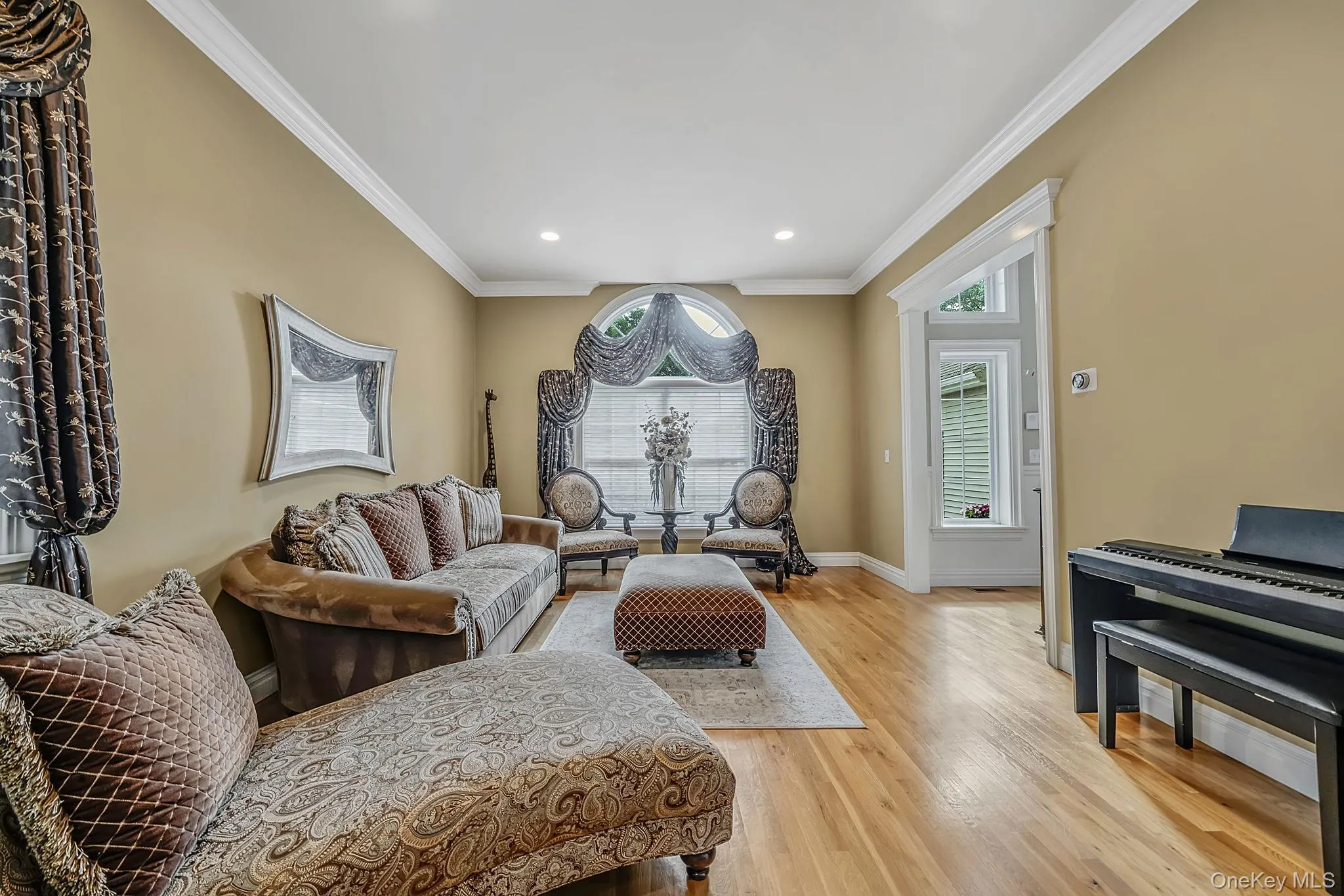 Elegant formal living room showcasing warm neutral walls, recessed ceiling lighting, and hardwood flooring Elegant formal living room showcasing warm neutral walls, recessed ceiling lighting, and hardwood flooring