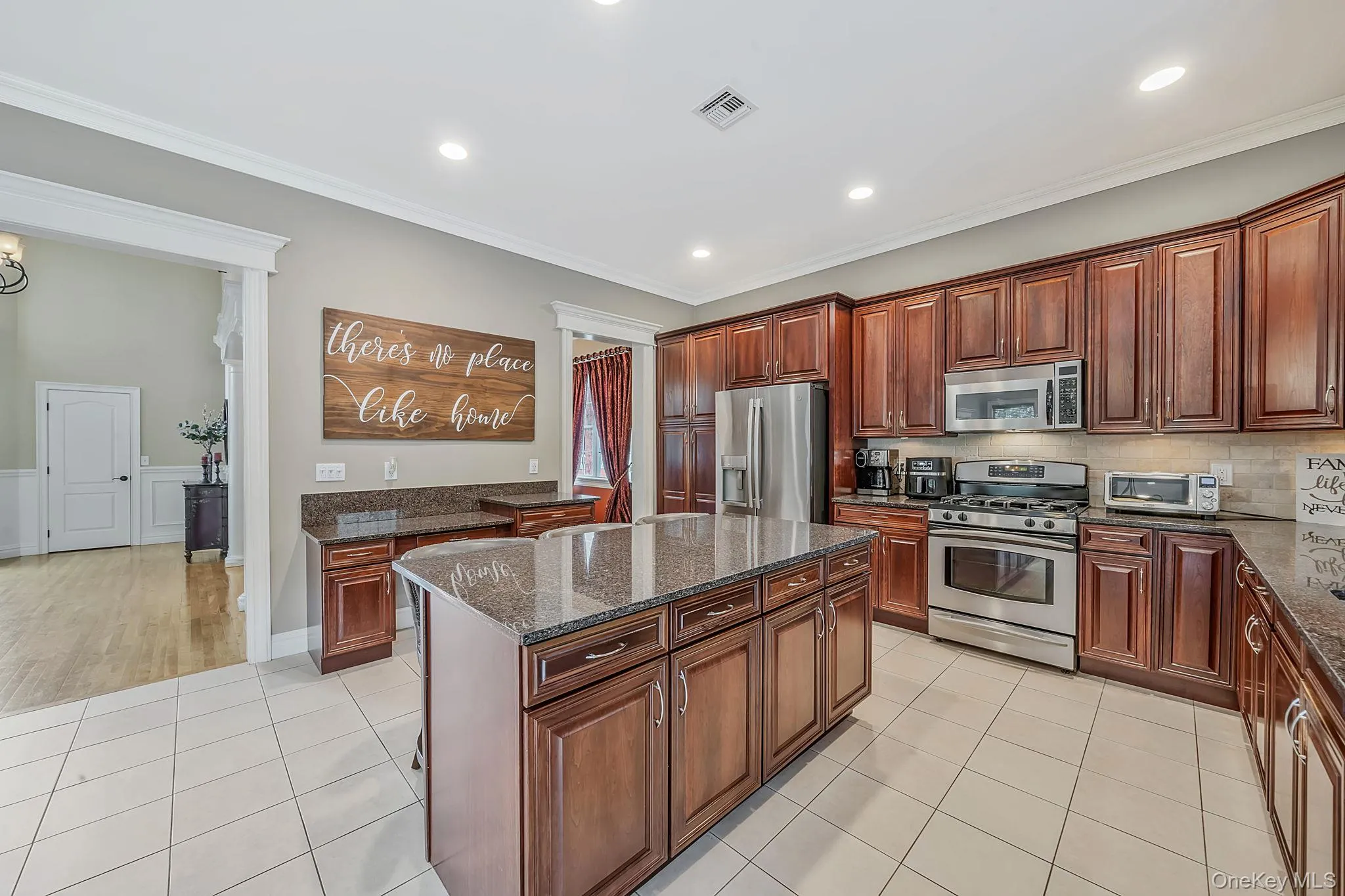 Kitchen featuring an expansive island with a granite countertop, wood-finish cabinetry, stainless steel appliances, recessed lighting, and tile flooring Kitchen featuring an expansive island with a granite countertop, wood-finish cabinetry, stainless steel appliances, recessed lighting, and tile flooring