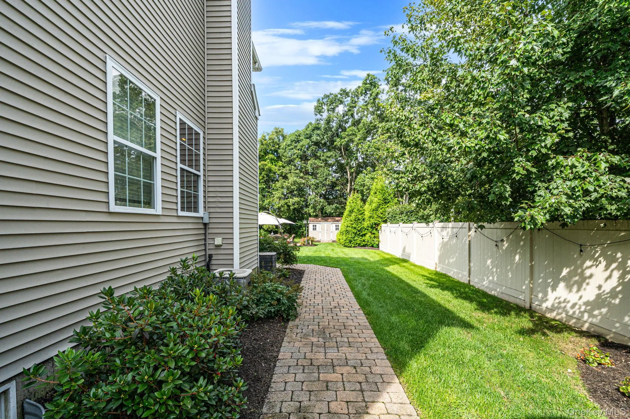 Exterior paver walkway, a privacy fence, and mature trees Exterior paver walkway, a privacy fence, and mature trees