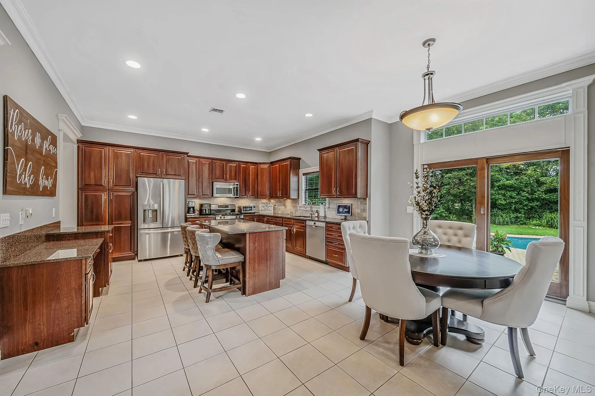 Kitchen featuring extensive wood cabinetry, stainless steel appliances, a large center island with a granite countertop, and tile flooring Kitchen featuring extensive wood cabinetry, stainless steel appliances, a large center island with a granite countertop, and tile flooring