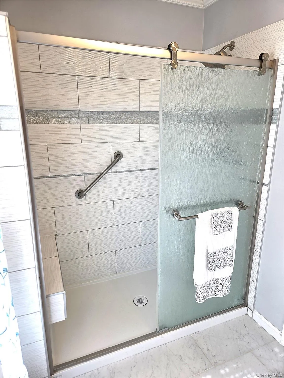 The Oversized Custom Shower In The Stunning, Completely Renovated & Upgraded Primary Bathroom With A Large Built In Seat & Beautiful Ceramic Tilework With An Accent Glass Tile Border. The Oversized Custom Shower In The Stunning, Completely Renovated & Upgraded Primary Bathroom With A Large Built In Seat & Beautiful Ceramic Tilework With An Accent Glass Tile Border.