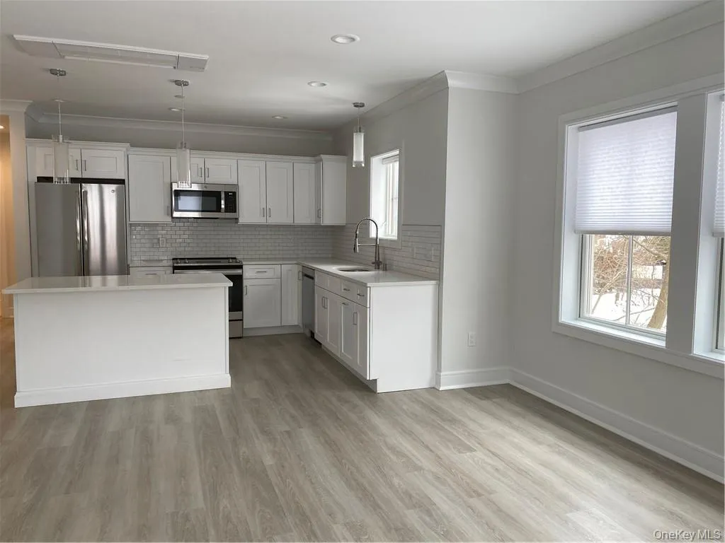 Kitchen with decorative backsplash, fridge, a center island, stove, and light hardwood / wood-style flooring Kitchen with decorative backsplash, fridge, a center island, stove, and light hardwood / wood-style flooring