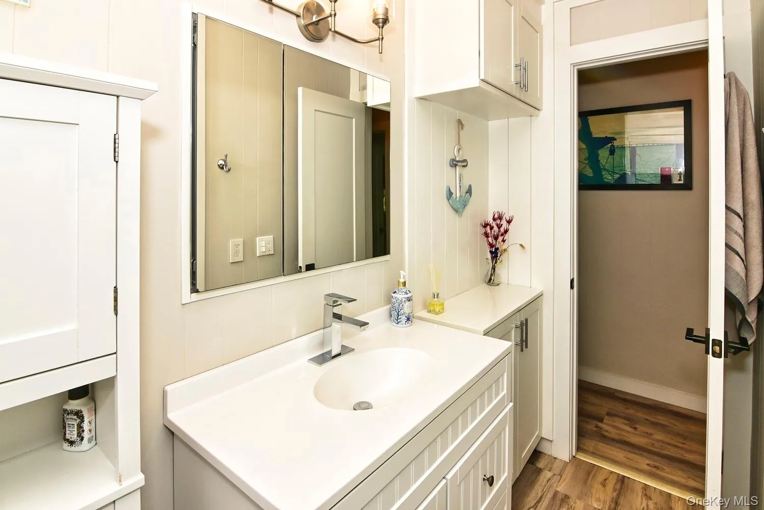 Spa-inspired bathroom featuring a single-sink vanity with white quartz countertop, polished chrome faucet, and ample storage cabinetry