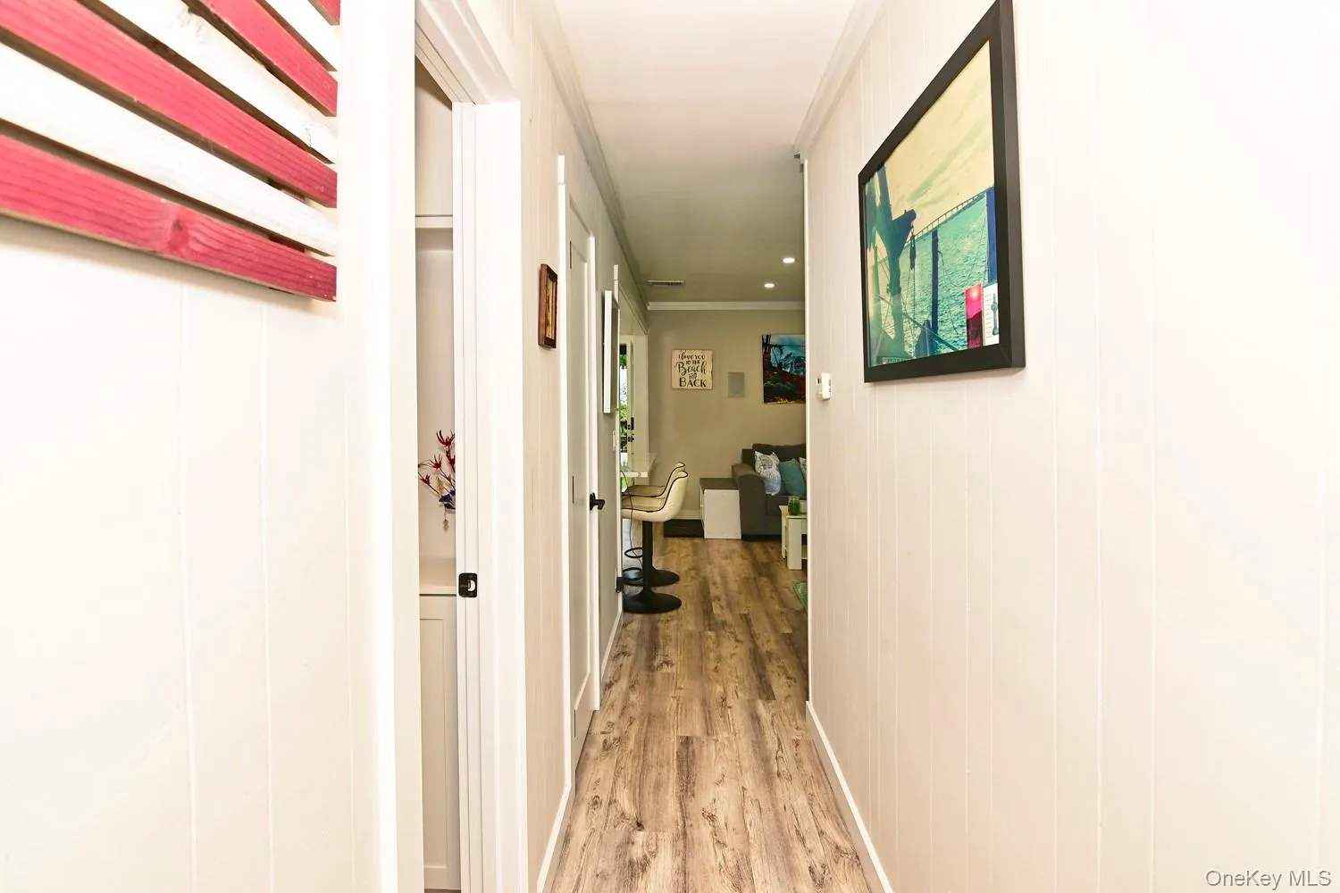 Bright hallway with wood-finish flooring, white walls, and recessed ceiling lighting