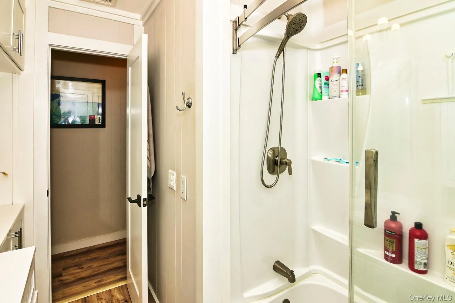 Modern bathroom featuring a frameless glass-enclosed shower with dual showerheads, brushed nickel fixtures, and white subway tile surround