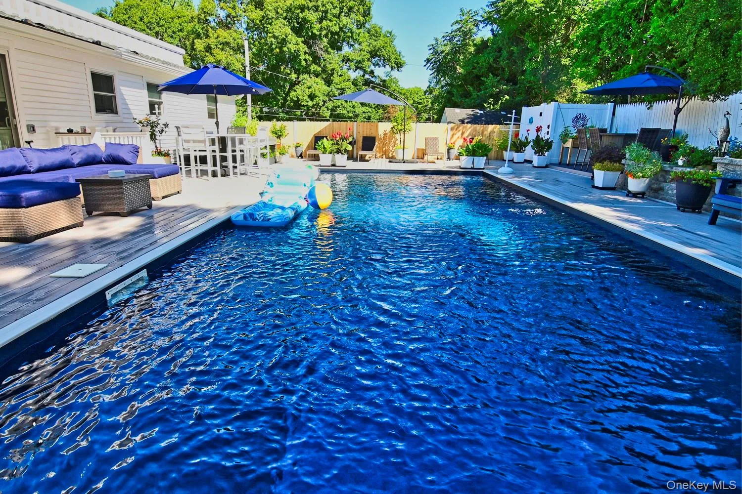 In-ground swimming pool with a surrounding Composite deck and white privacy fencing