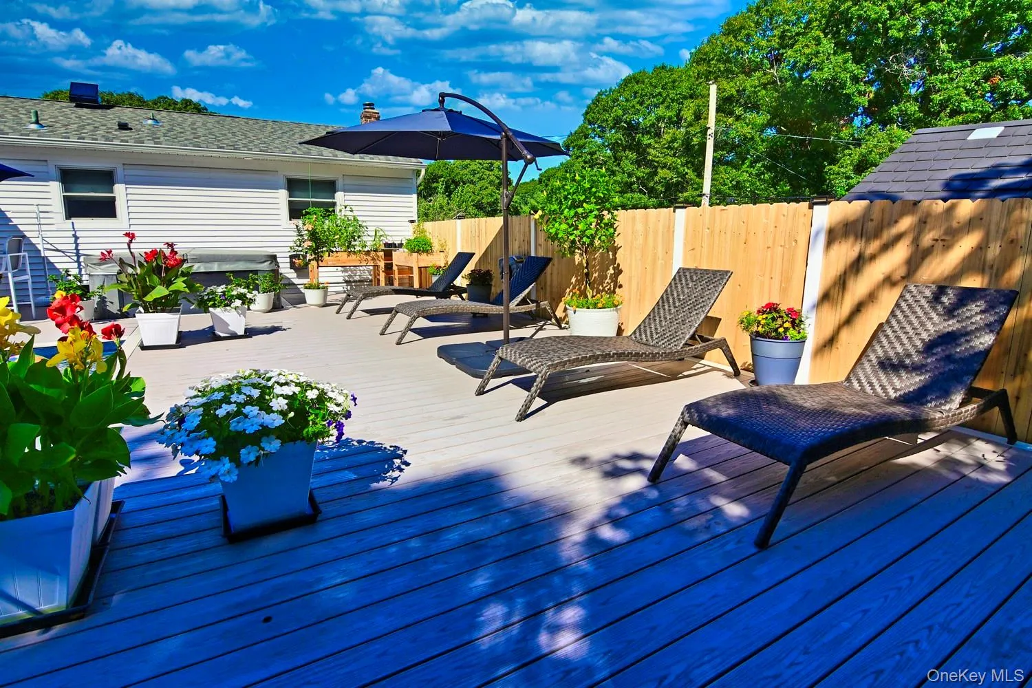 Spacious outdoor deck with composite decking, privacy fencing, and an umbrella shading a lounge area