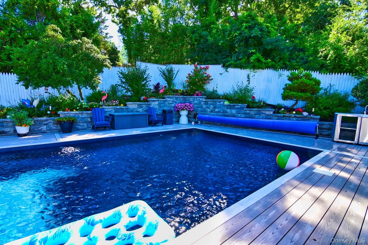 In-ground swimming pool featuring deep blue water, composite decking, and curved blue tile accents