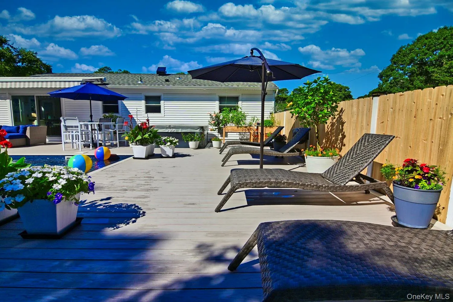 Composite deck with a built-in pool, white siding exterior, and a privacy fence