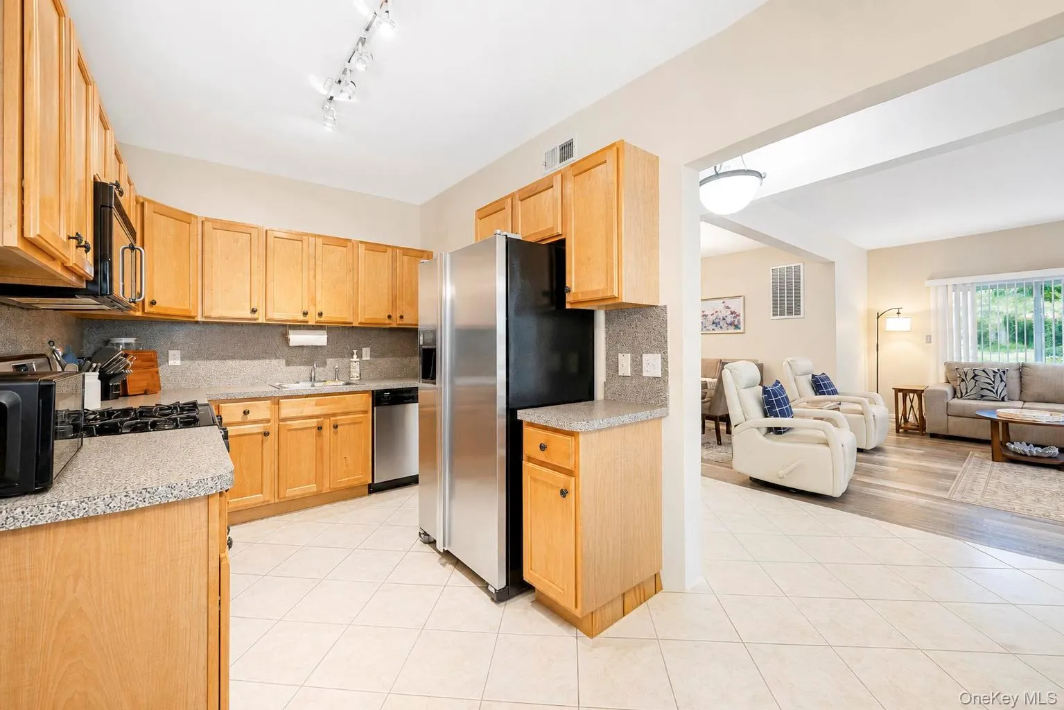 Kitchen featuring wood cabinetry, stainless steel appliances, and tile flooring Kitchen featuring wood cabinetry, stainless steel appliances, and tile flooring