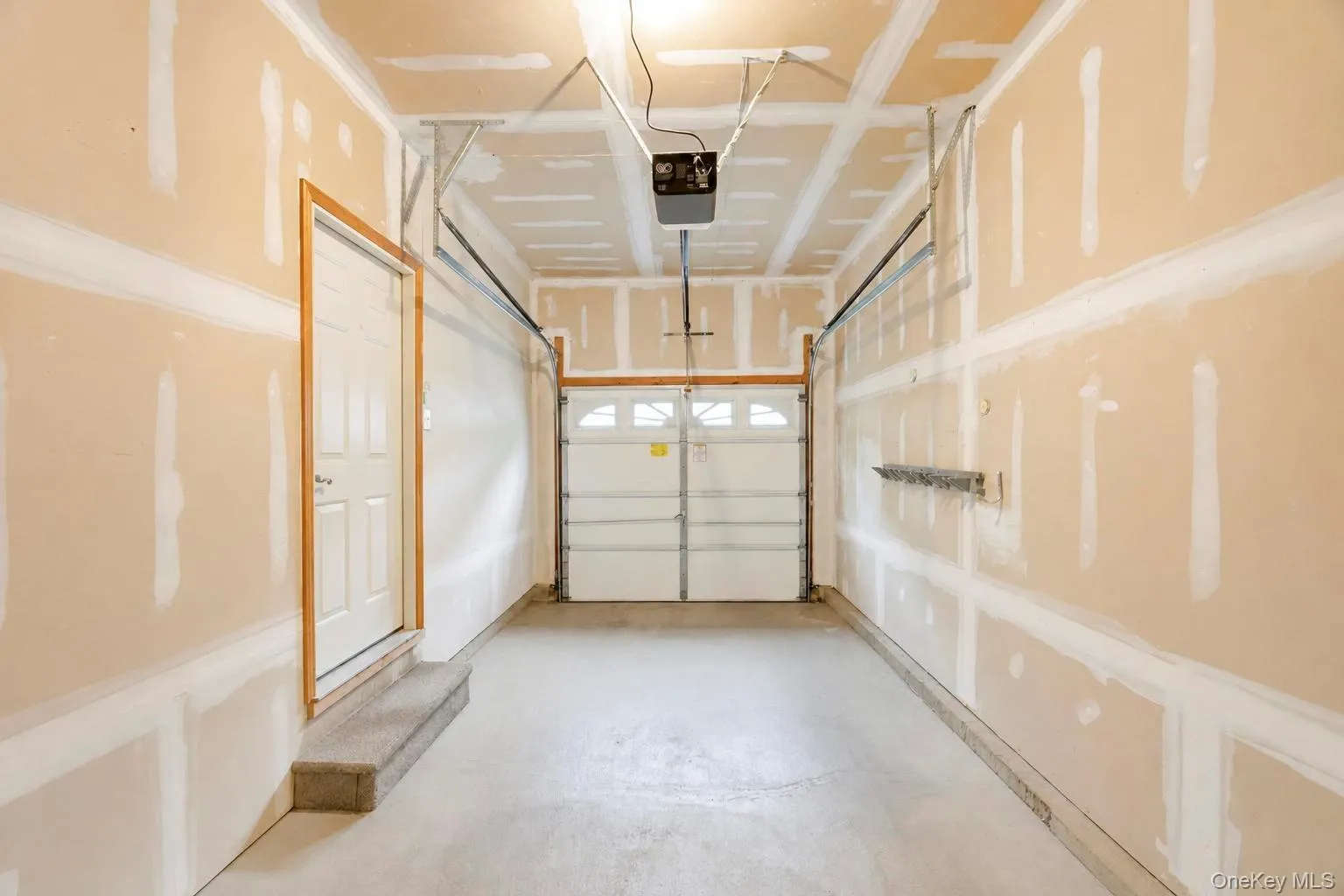 Attached garage space featuring an overhead door, concrete flooring, and an interior access door Attached garage space featuring an overhead door, concrete flooring, and an interior access door