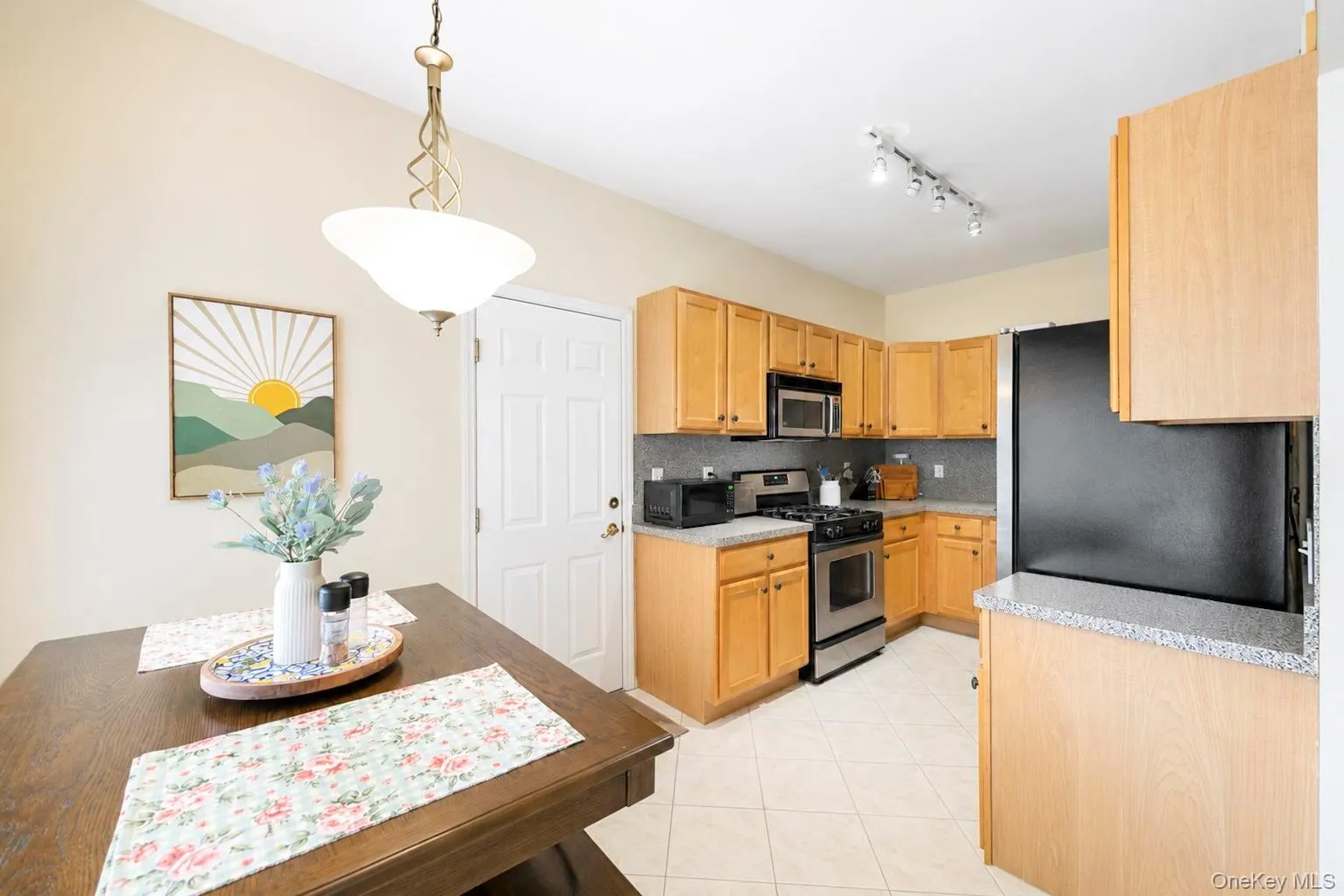 Kitchen featuring wood-finish cabinetry, stainless steel appliances, and a tiled flooring Kitchen featuring wood-finish cabinetry, stainless steel appliances, and a tiled flooring