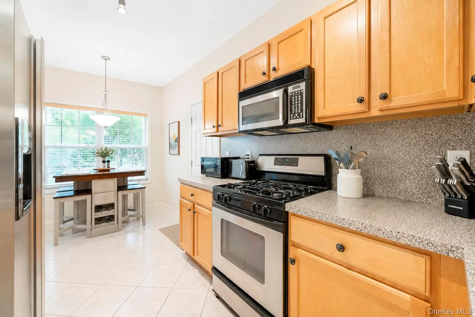 Light wood cabinetry, stainless steel appliances, and tiled flooring Light wood cabinetry, stainless steel appliances, and tiled flooring