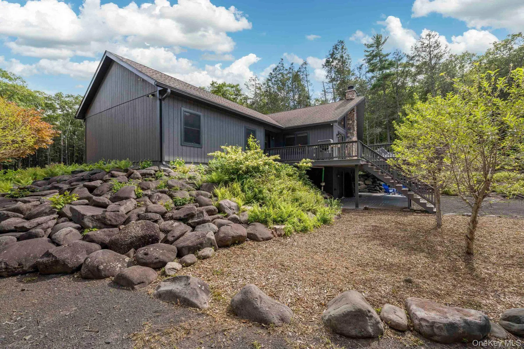Natural stonework and established plantings frame the rear of the home and create a landscaped transition into the surrounding wooded setting. Natural stonework and established plantings frame the rear of the home and create a landscaped transition into the surrounding wooded setting.