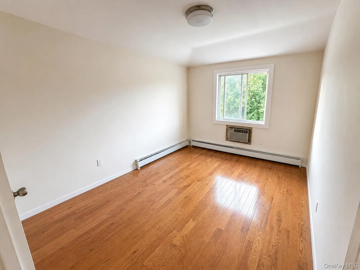 Hardwood flooring, white walls, and a window unit air conditioner Hardwood flooring, white walls, and a window unit air conditioner