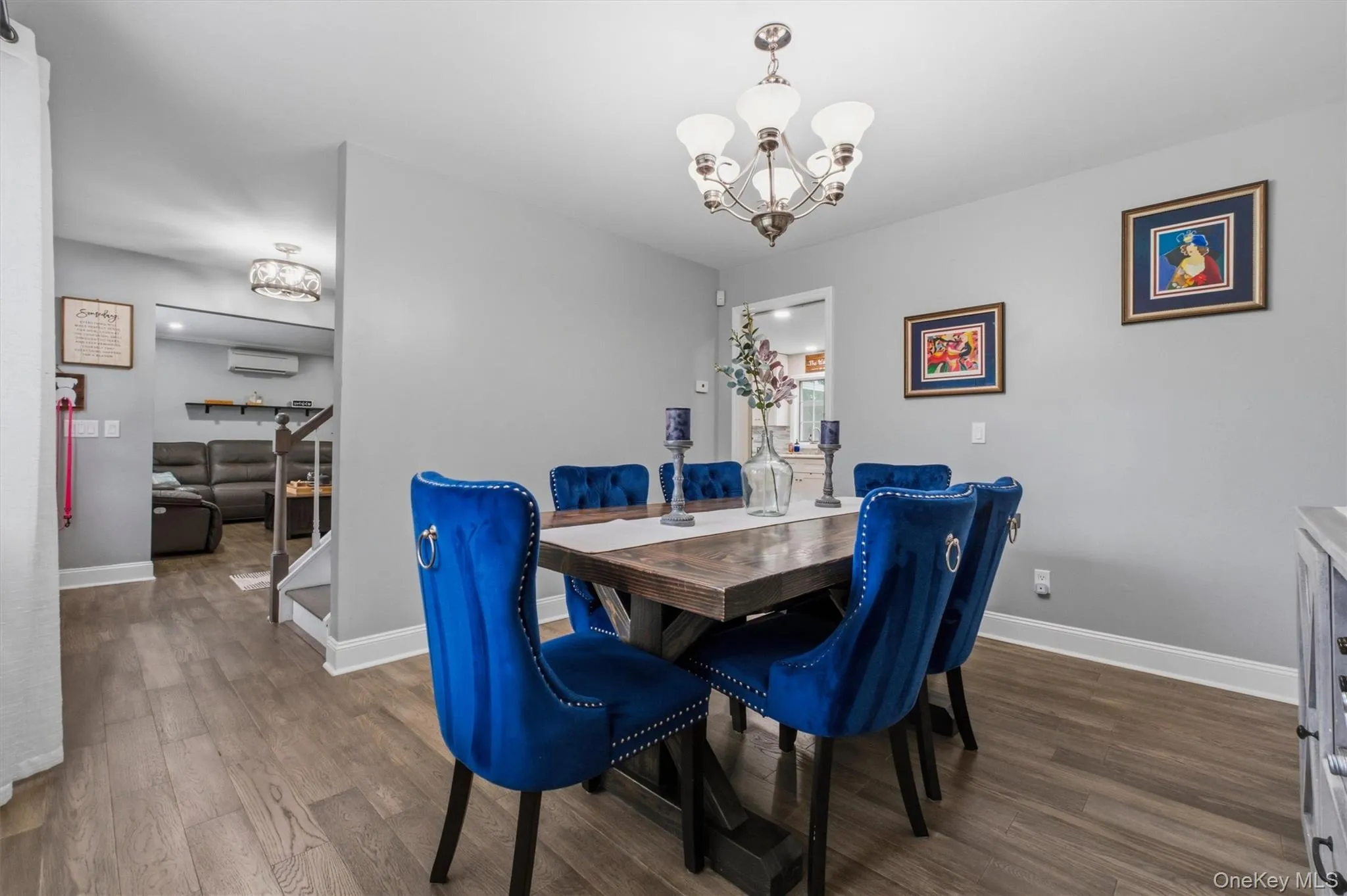 Dining area featuring wood-finish flooring, a contemporary chandelier, and light gray wall finishes Dining area featuring wood-finish flooring, a contemporary chandelier, and light gray wall finishes