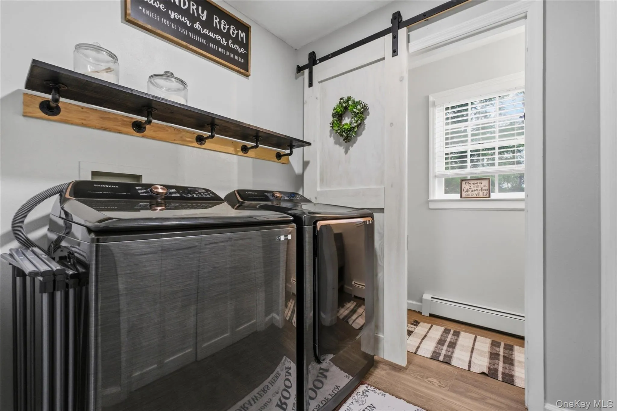 Wood-finish flooring with a white barn door on a black rail system Wood-finish flooring with a white barn door on a black rail system