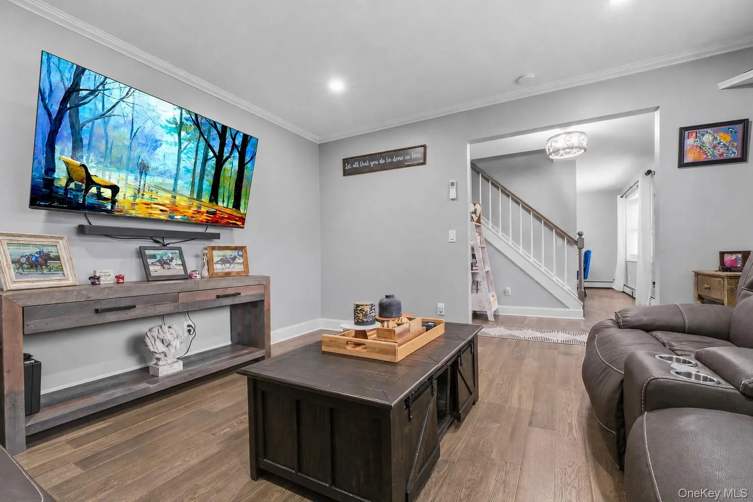 Wood-finish flooring, recessed lighting, crown molding, open archway, and a built-in staircase Wood-finish flooring, recessed lighting, crown molding, open archway, and a built-in staircase
