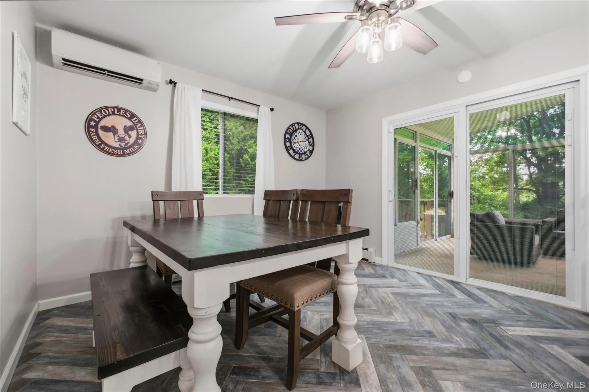 Herringbone wood-finish flooring, ceiling fan with integrated lighting, sliding glass door, and wall-mounted air conditioning unit Herringbone wood-finish flooring, ceiling fan with integrated lighting, sliding glass door, and wall-mounted air conditioning unit