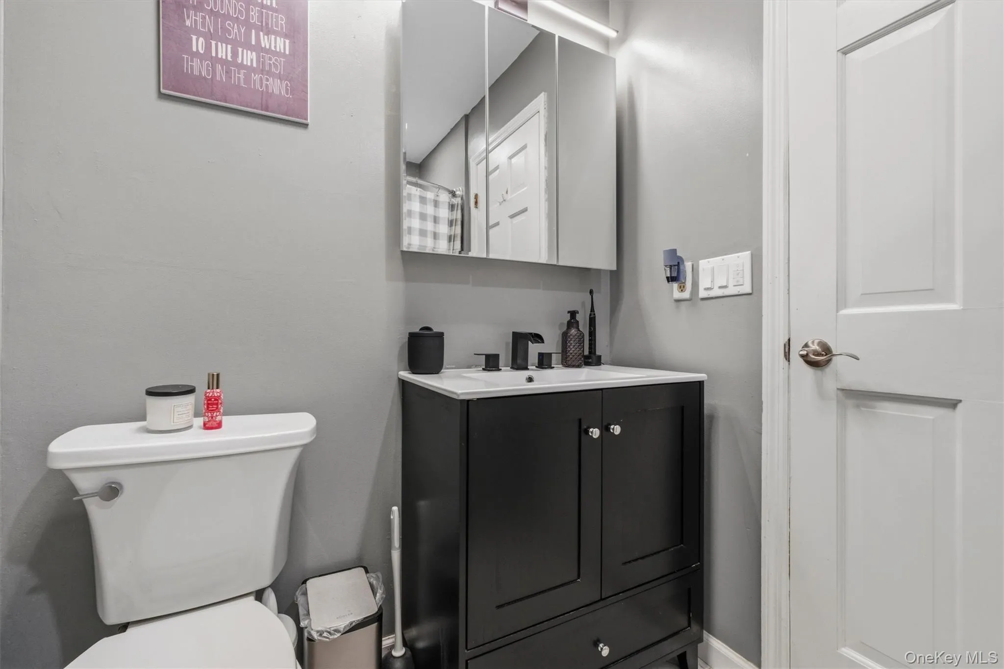 Modern bathroom featuring a black vanity with a white integrated sink, matte black faucet, and a wall-mounted mirrored medicine cabinet Modern bathroom featuring a black vanity with a white integrated sink, matte black faucet, and a wall-mounted mirrored medicine cabinet