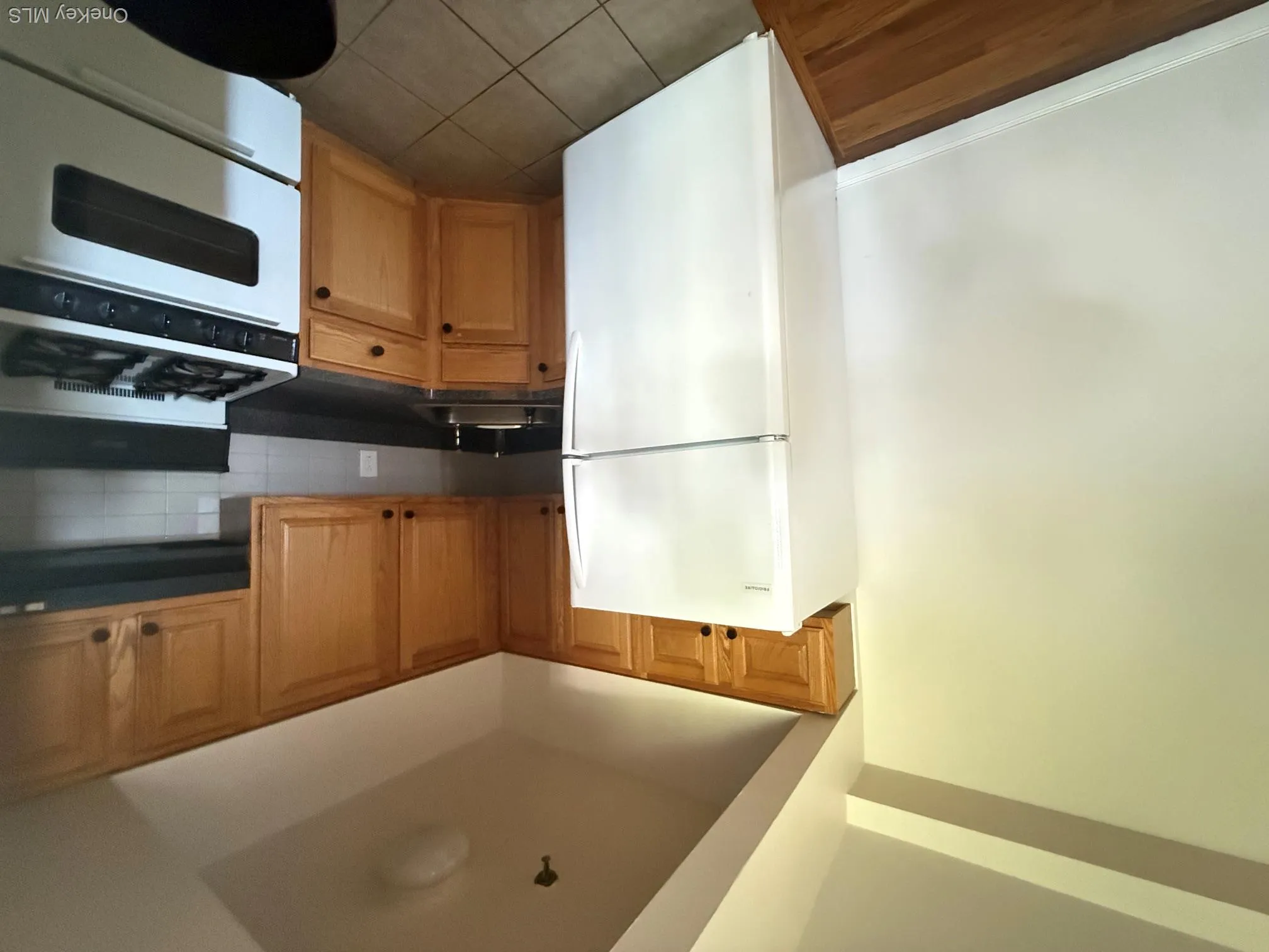 Wood-finish flooring, white walls, light wood cabinetry, white appliances, and tiled flooring Wood-finish flooring, white walls, light wood cabinetry, white appliances, and tiled flooring