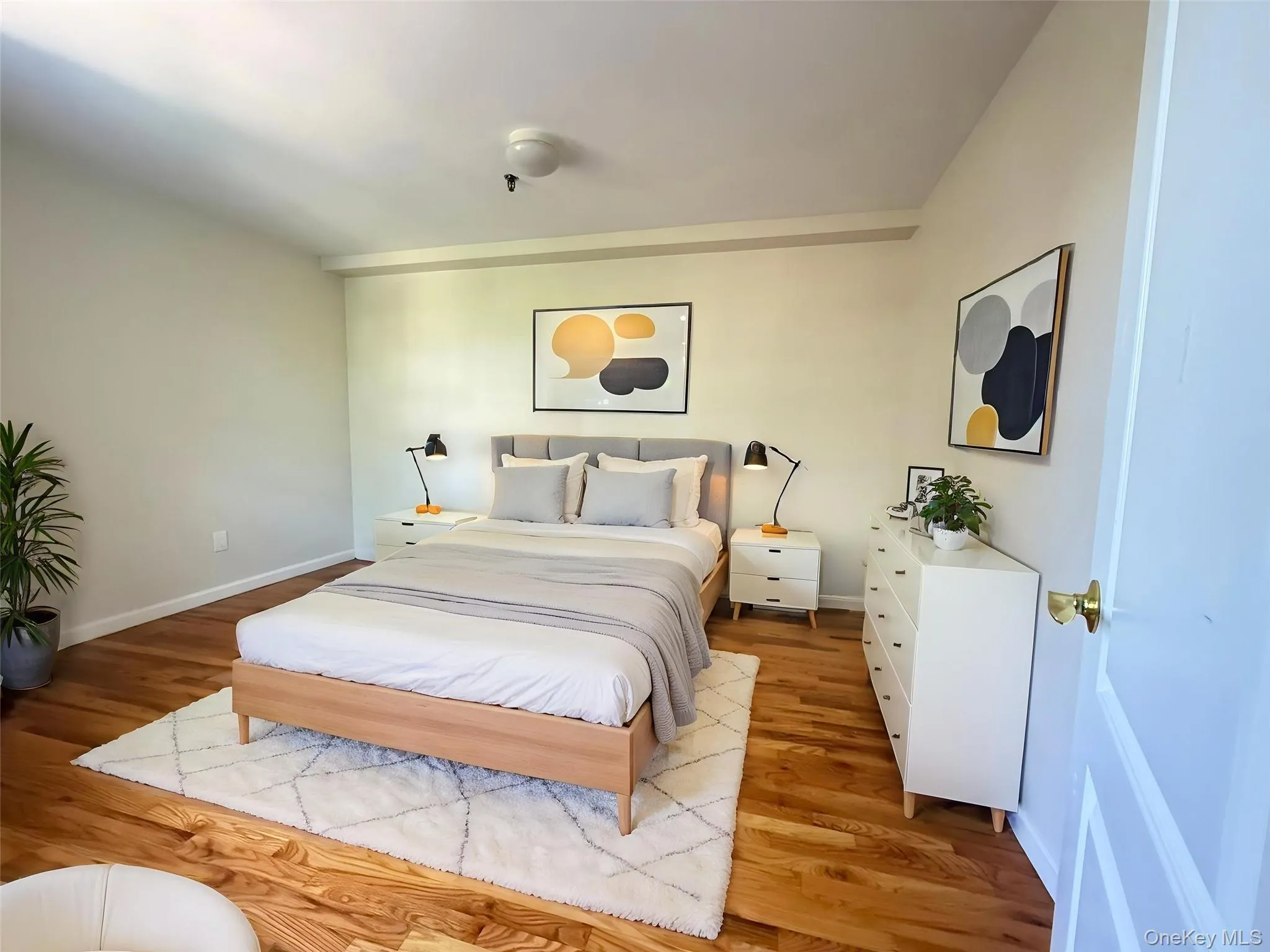 Hardwood flooring and light-toned walls create a neutral backdrop in this space, complemented by a ceiling-mounted light fixture Hardwood flooring and light-toned walls create a neutral backdrop in this space, complemented by a ceiling-mounted light fixture