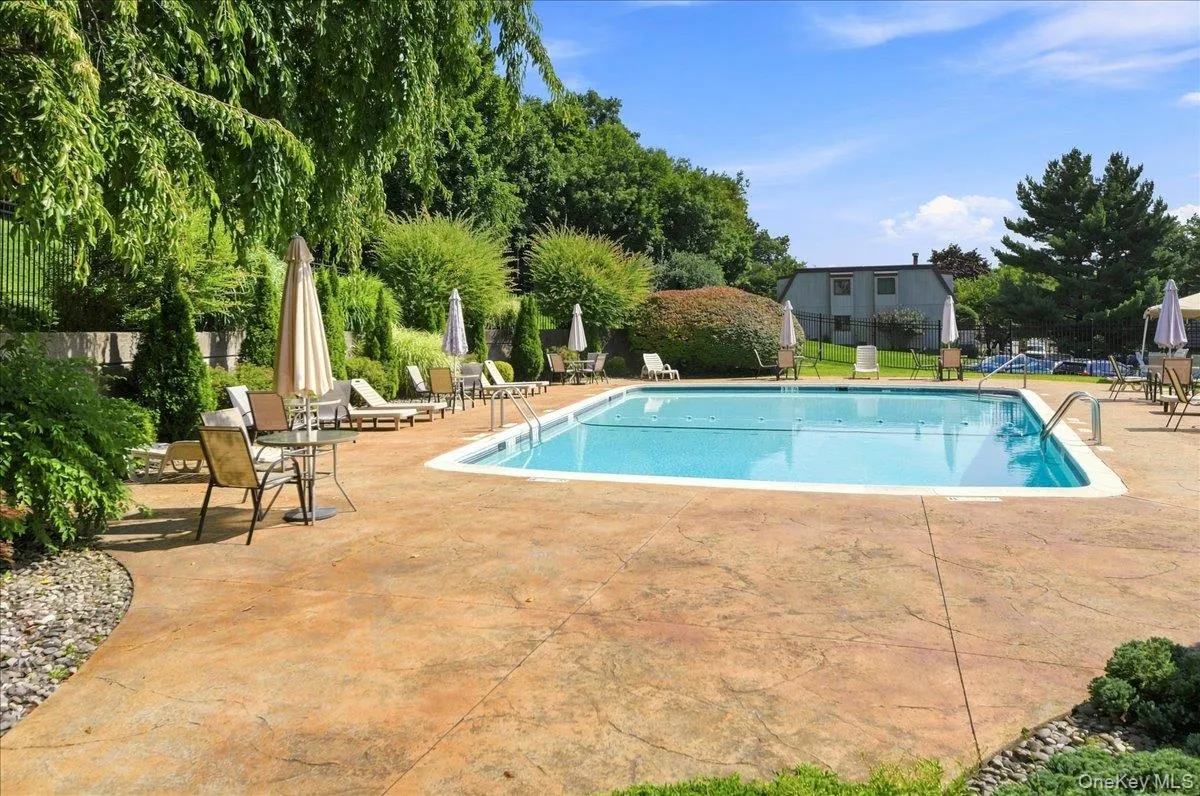 Outdoor swimming pool featuring a patterned concrete surround and lush perimeter landscaping Outdoor swimming pool featuring a patterned concrete surround and lush perimeter landscaping