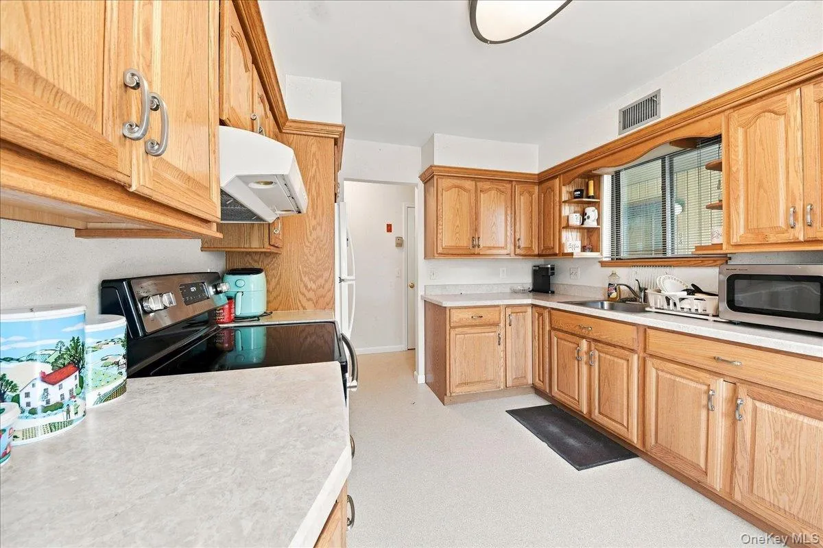 Full kitchen featuring wood cabinetry and light-toned countertops Full kitchen featuring wood cabinetry and light-toned countertops
