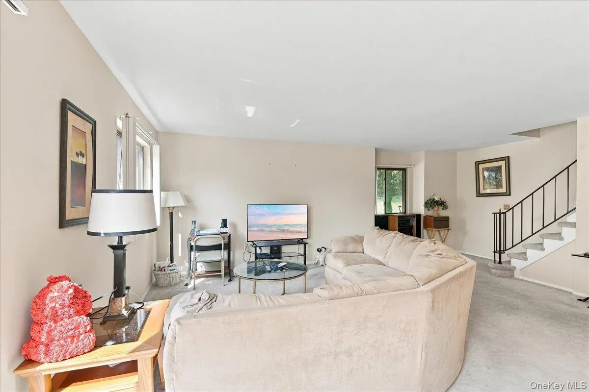 Carpet flooring, neutral painted walls, windows, and an interior staircase with metal railing Carpet flooring, neutral painted walls, windows, and an interior staircase with metal railing