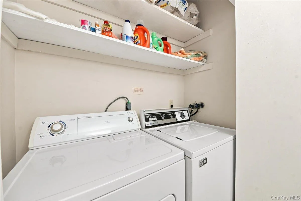 Laundry area with open shelving and white appliances Laundry area with open shelving and white appliances